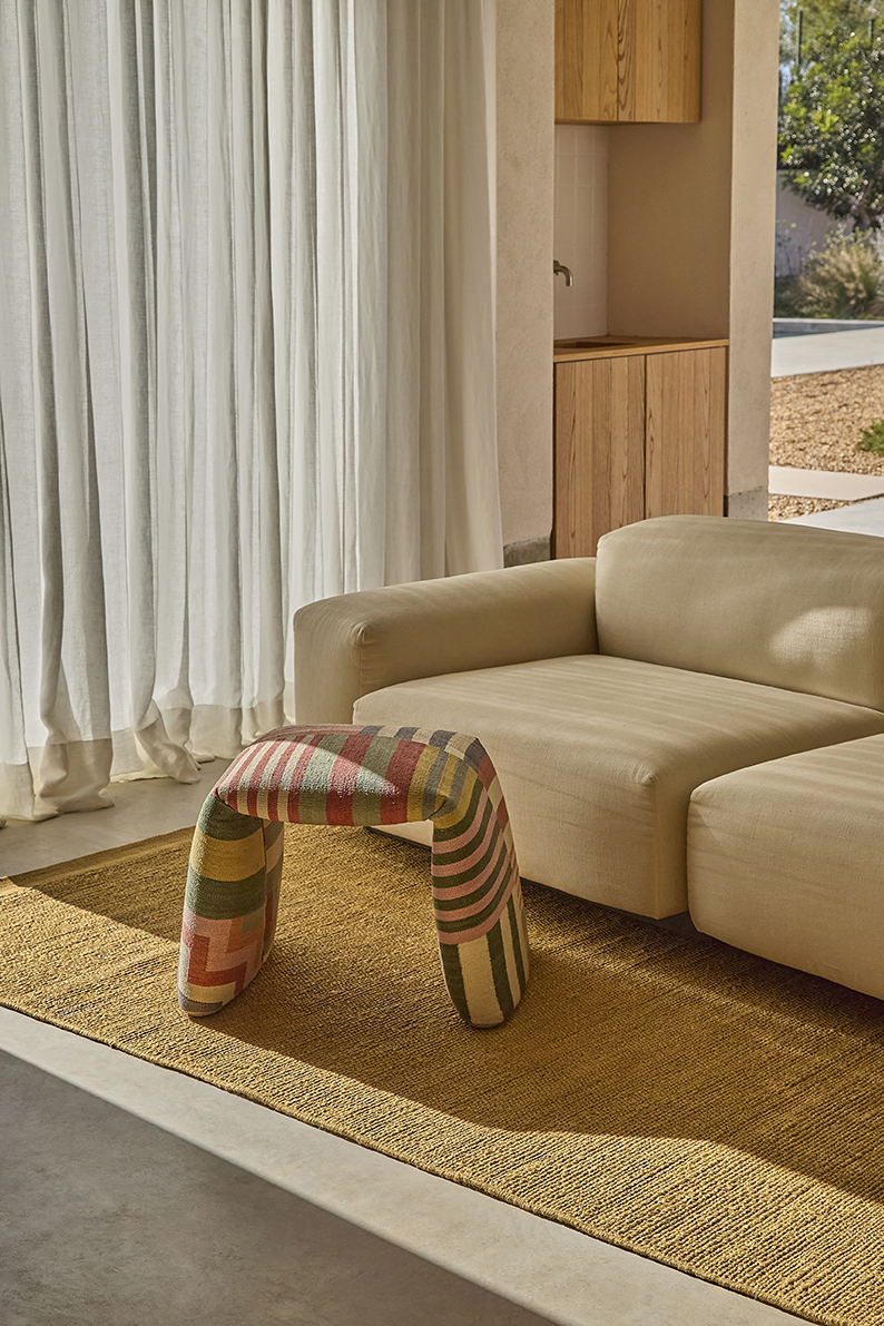 Nanimarquina Bank: Gepolsterte Sitzbank mit farbigem Muster, passend zum Teppich und Sofa.