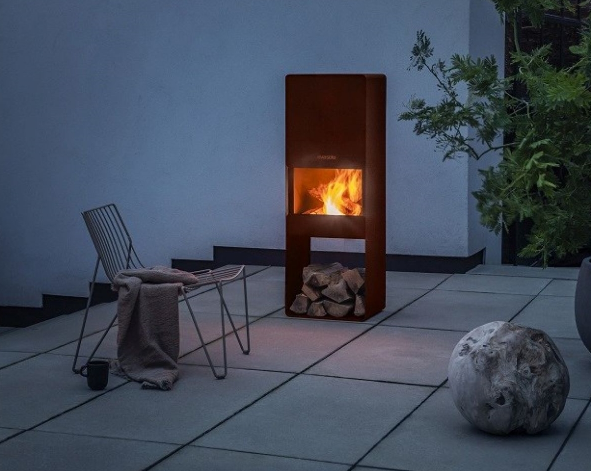 Moderner Außenkamin aus Cortenstahl mit Holzscheitlagerung und brennendem Feuer für gemütliche Stunden im Garten.