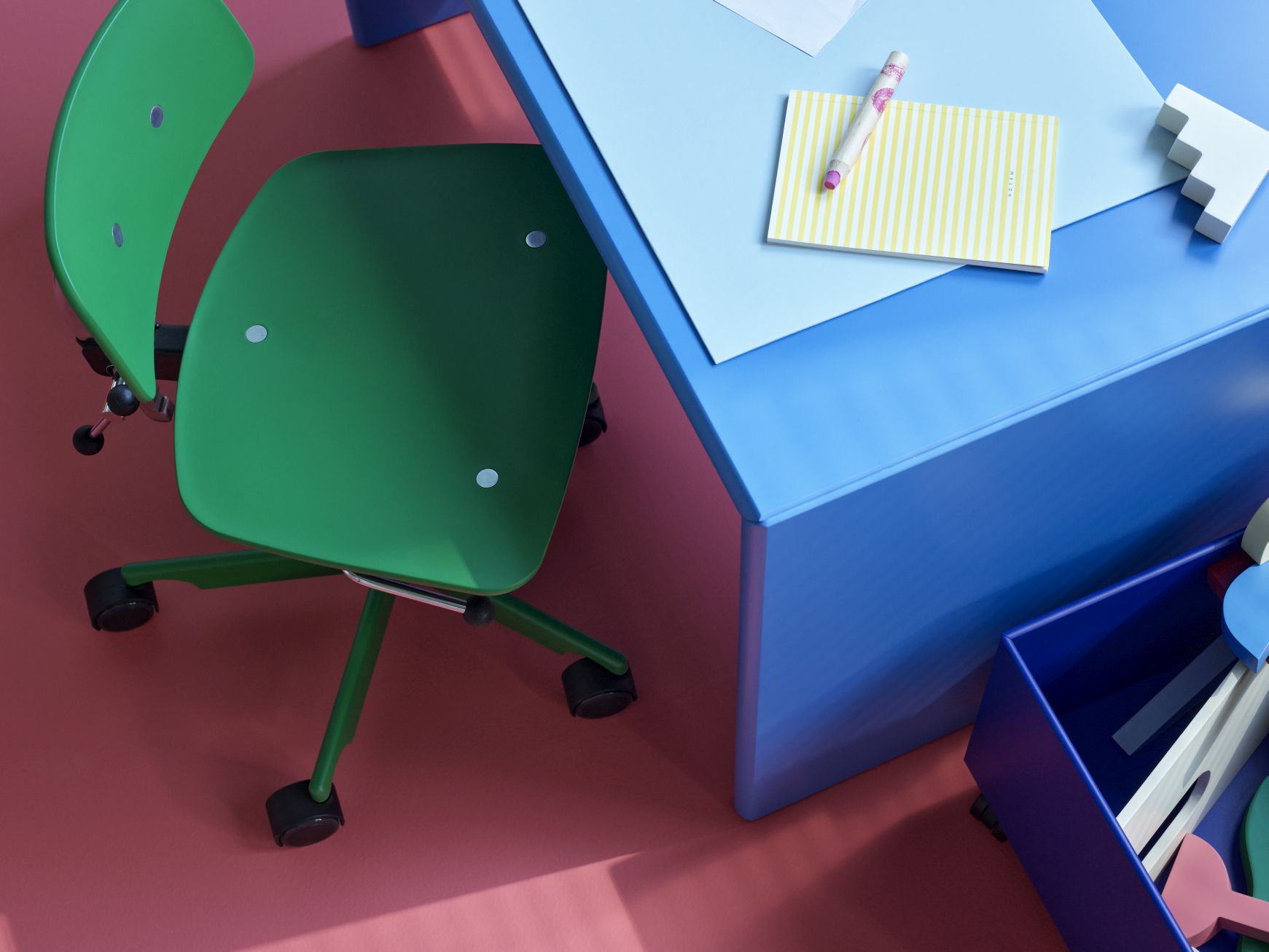 Nahaufnahme einer blauen Montana Mini Play Aufbewahrungsbox mit Spielzeug neben einem Schreibtisch und Stuhl.