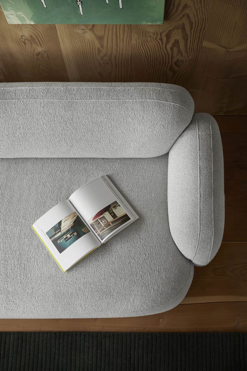 Draufsicht: Gem Sofa, 3-Sitzer, braun, mit offenem Buch auf der Sitzfläche. Modernes Wohnzimmer.