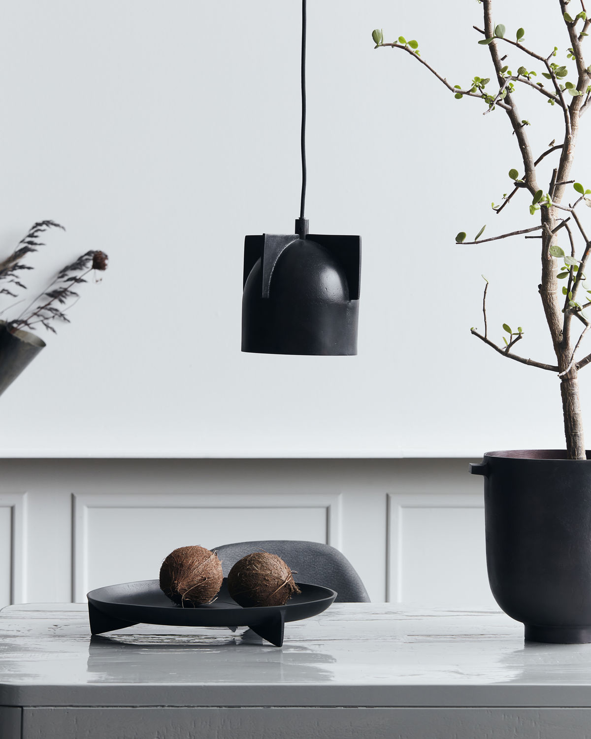 Akola Pendelleuchte von House Doctor, schwarze Hängelampe über Tisch mit Dekoration.