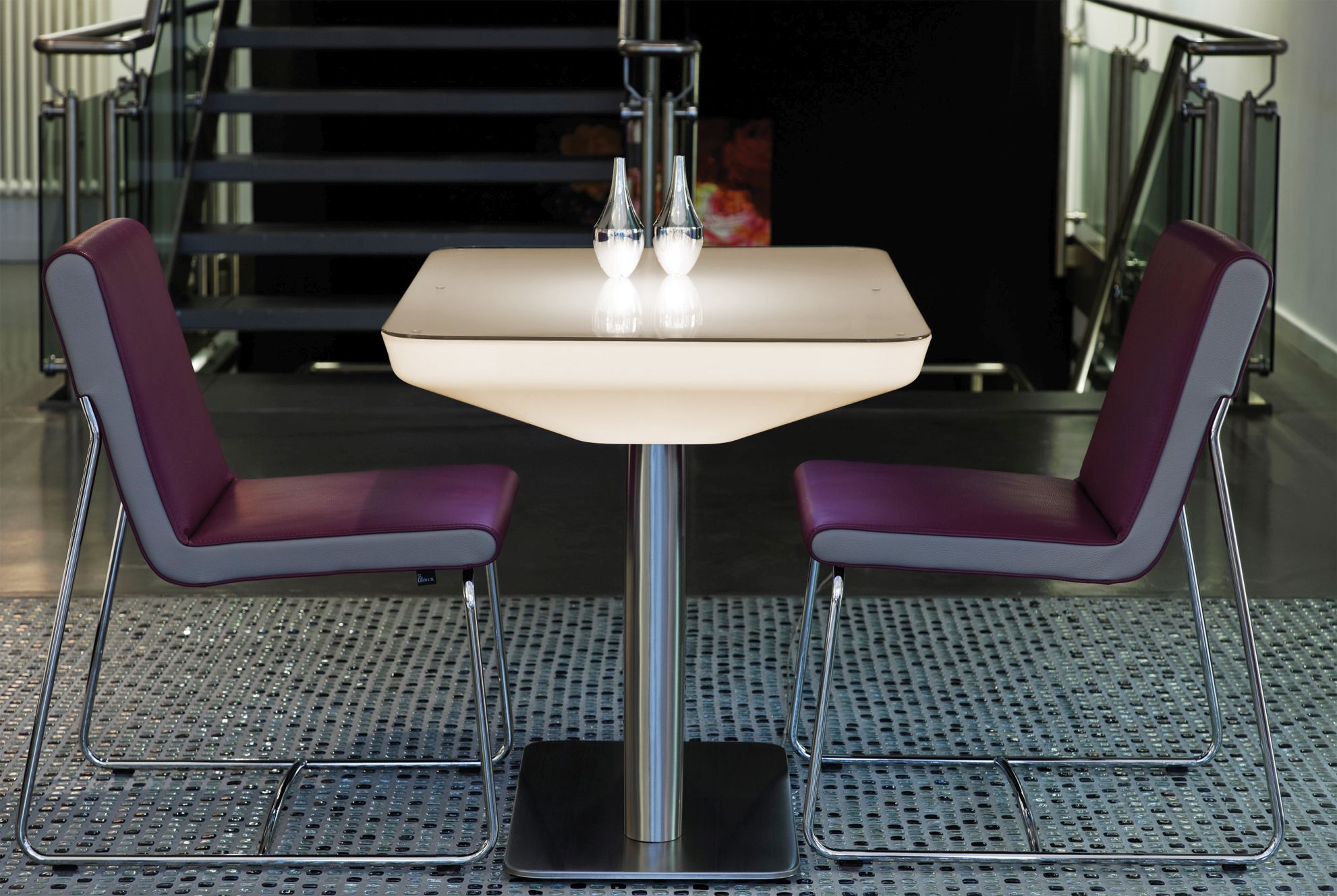 Studio 75 LED Tisch von Moree, beleuchtet, mit zwei Stühlen und Dekoration.