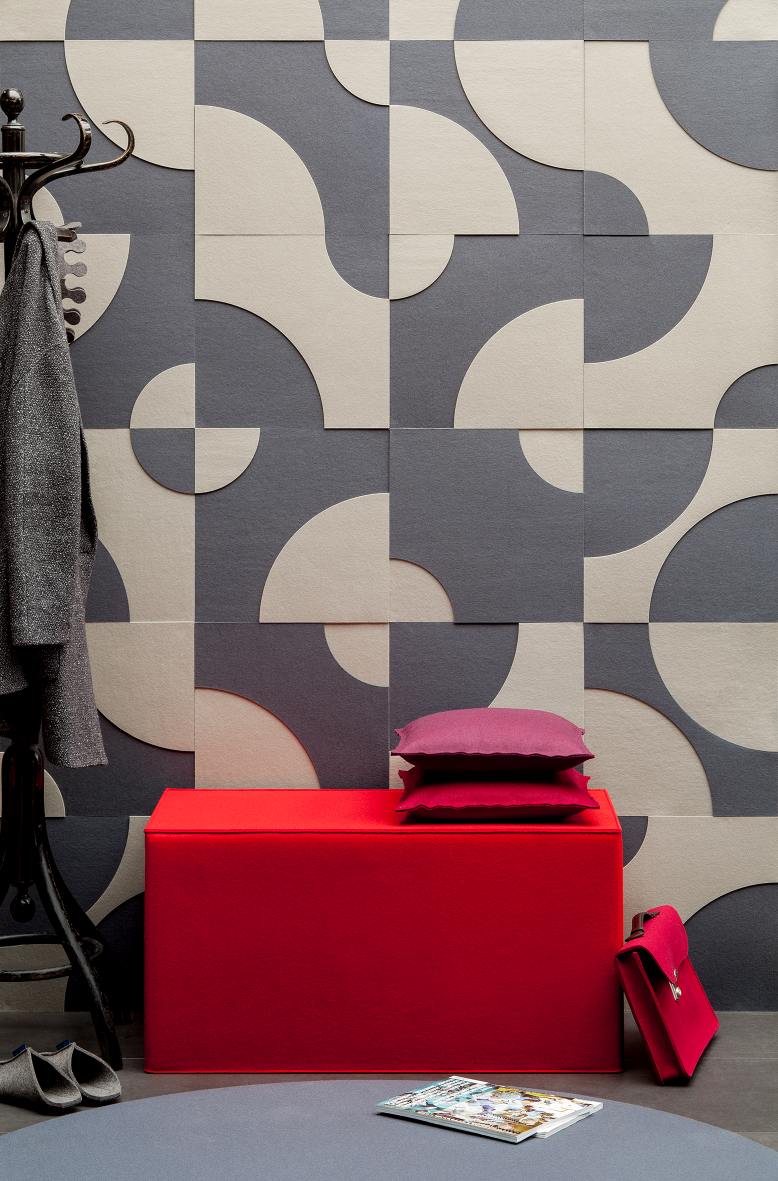 Roter Quader Sitzhocker von Hey Sign mit Kissen vor gemusterter Wand. Filzhocker als Sitzmöbel.