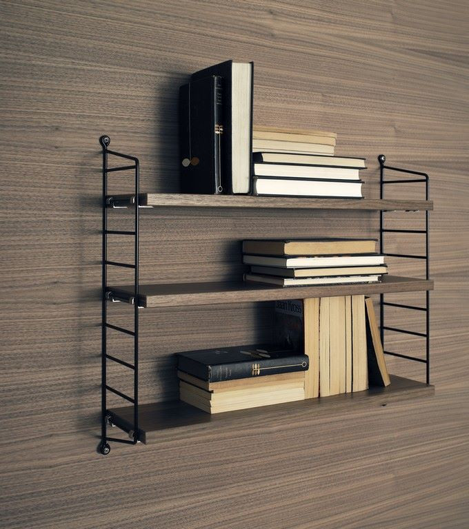 String Pocket Regal mit Bücher auf drei Regalböden vor einer Holzwand.