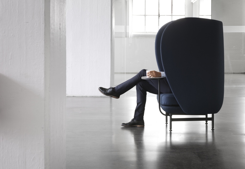 JH1001 Plenum Sessel von Fritz Hansen in Blau mit Person und kleinem Tisch.