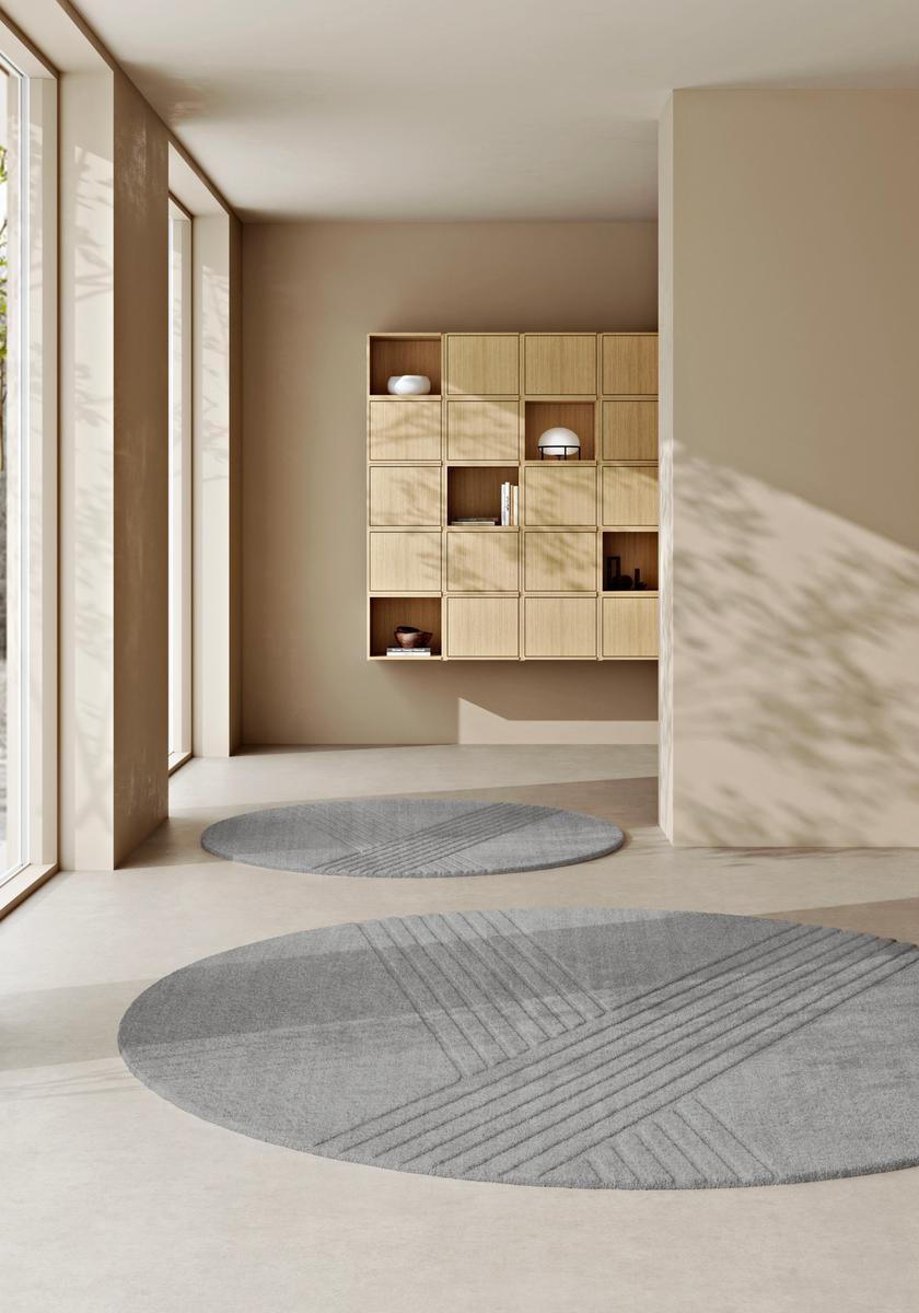 Zwei graue, runde Kyoto Teppiche von Woud mit geometrischem Muster in einem minimalistischen Raum.