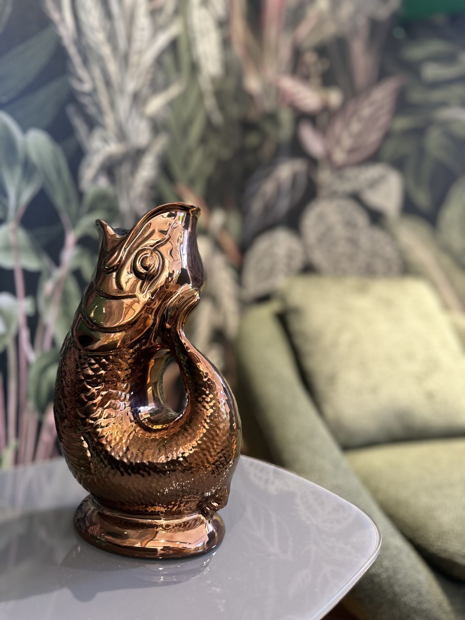 Kupferfarbene Gluckigluck Fischkaraffe auf einem Tisch, dekorative Wasserkaraffe im Fischdesign.