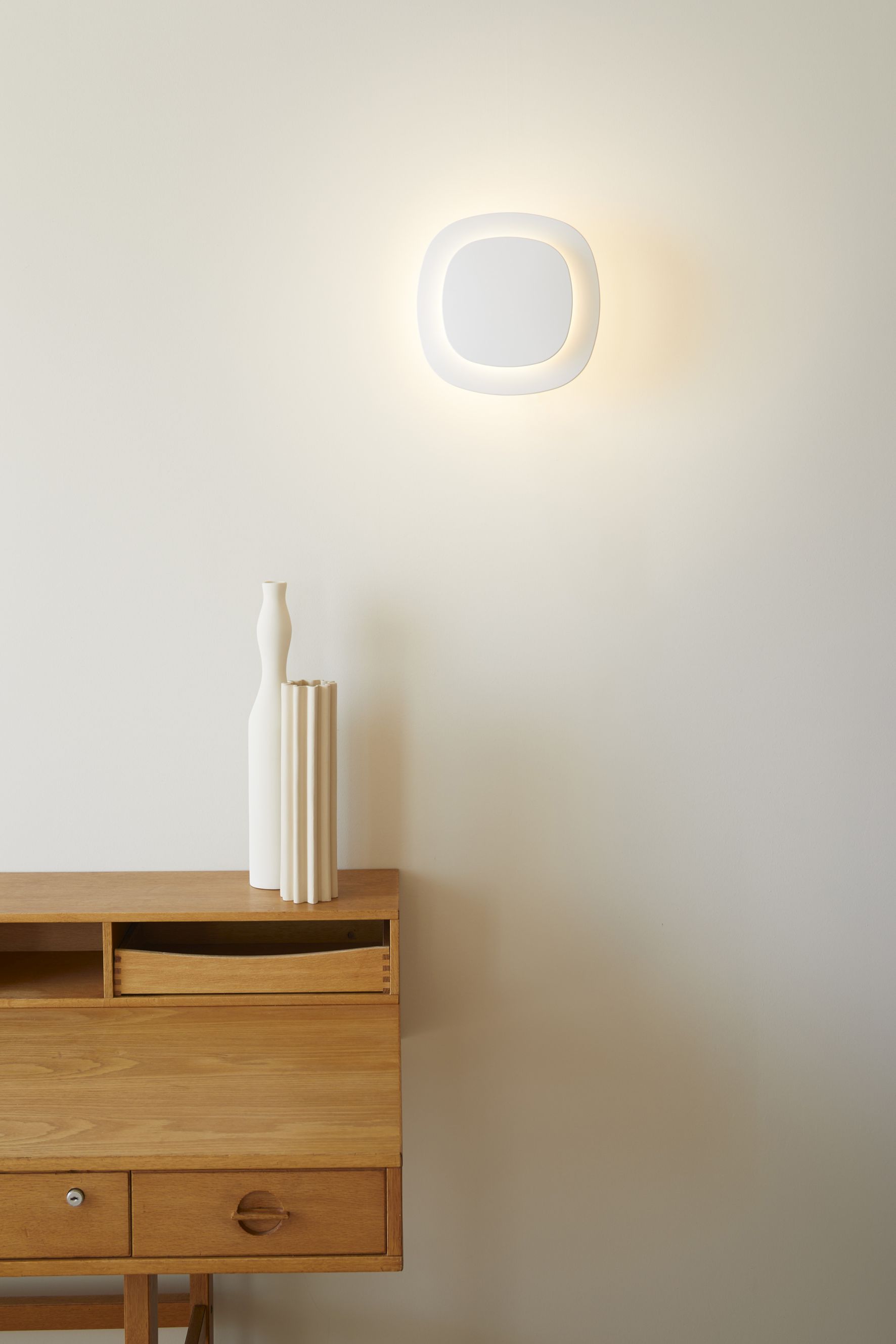 Weiße D85 Luthien Wandleuchte von Luceplan an der Wand, warmes Licht, modernes Design.