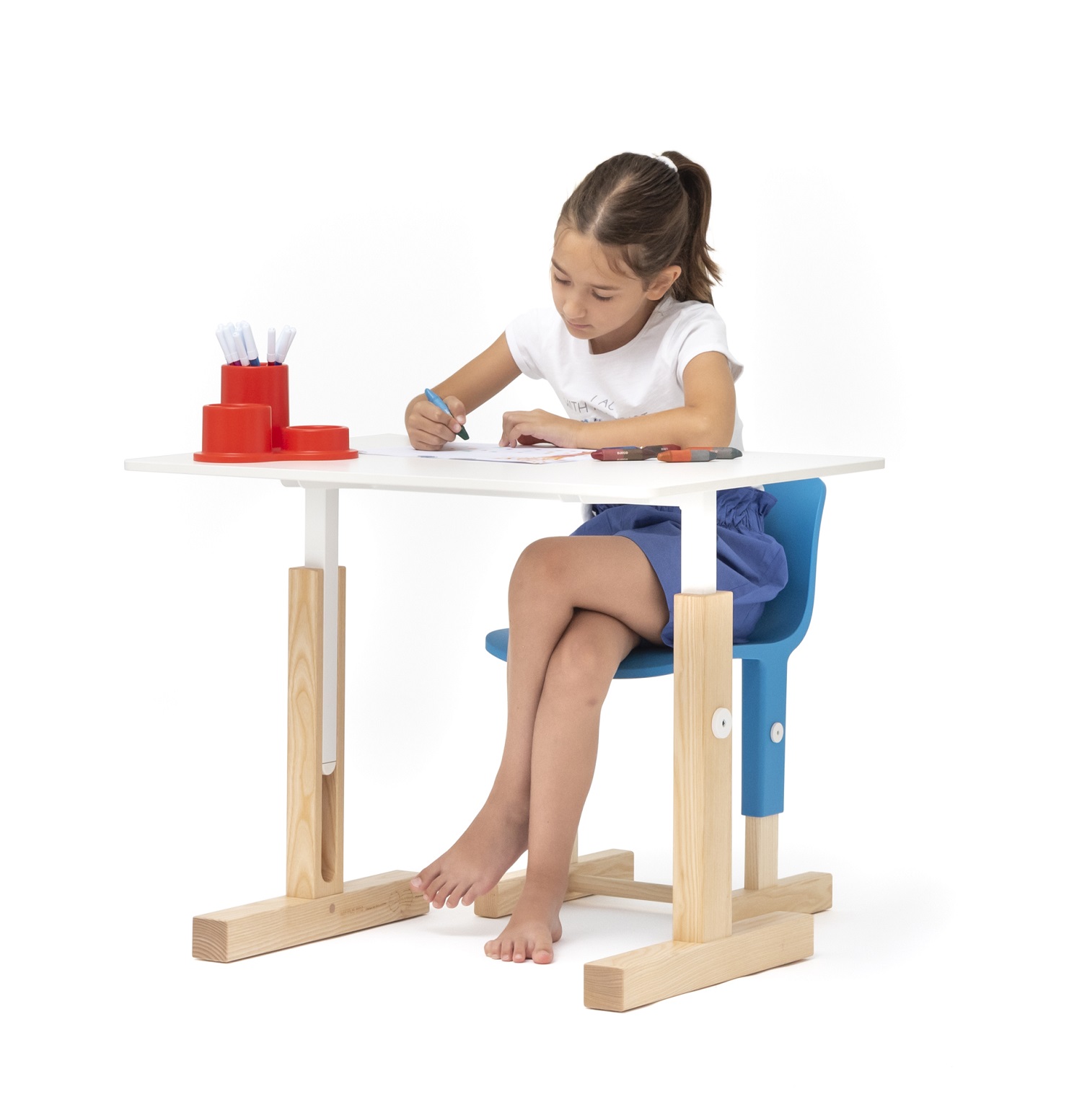Mädchen malt am weißen, höhenverstellbaren Kinderstuhl von Magis. Ergonomischer Kinderstuhl für gesundes Sitzen.