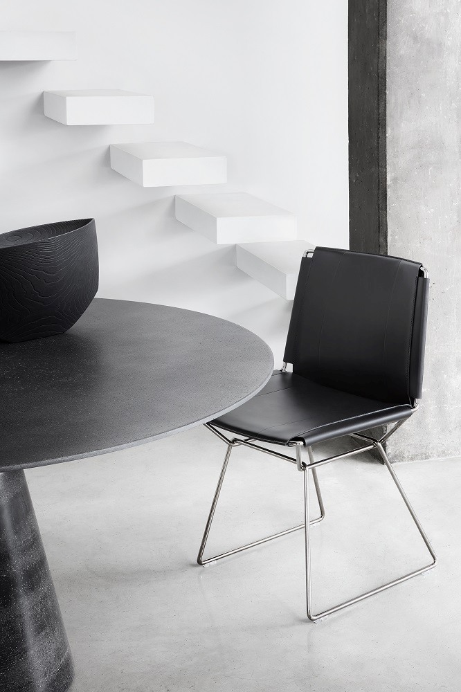 Schwarzer Lederstuhl mit Metallgestell neben einem Esstisch. Moderner Design Stuhl.