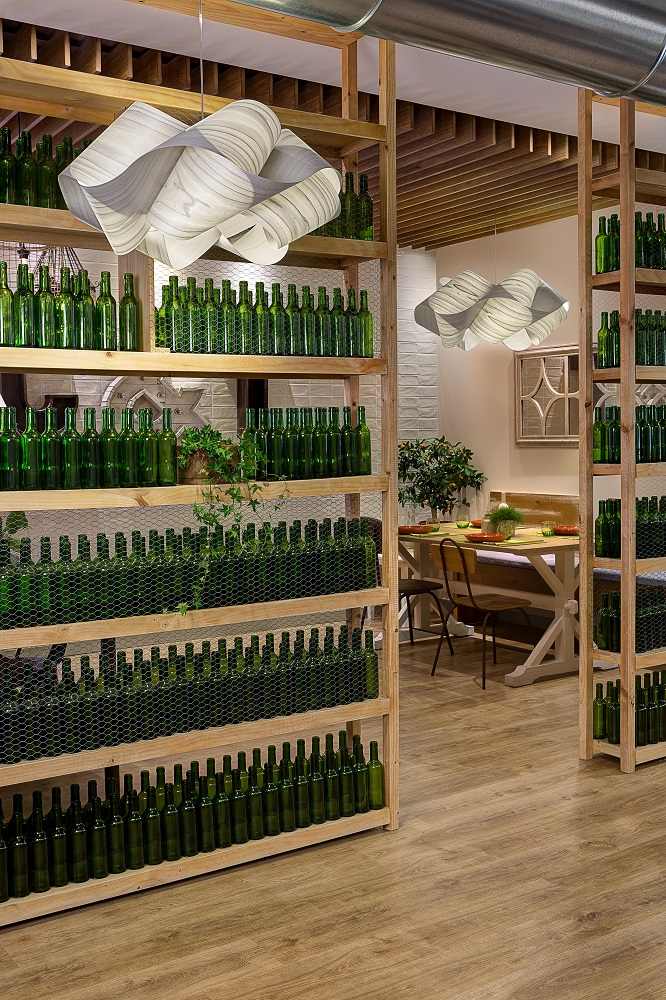 Swirl Pendelleuchte von LZF Lamps, moderne Hängeleuchte in einem Restaurant mit grünen Flaschen.