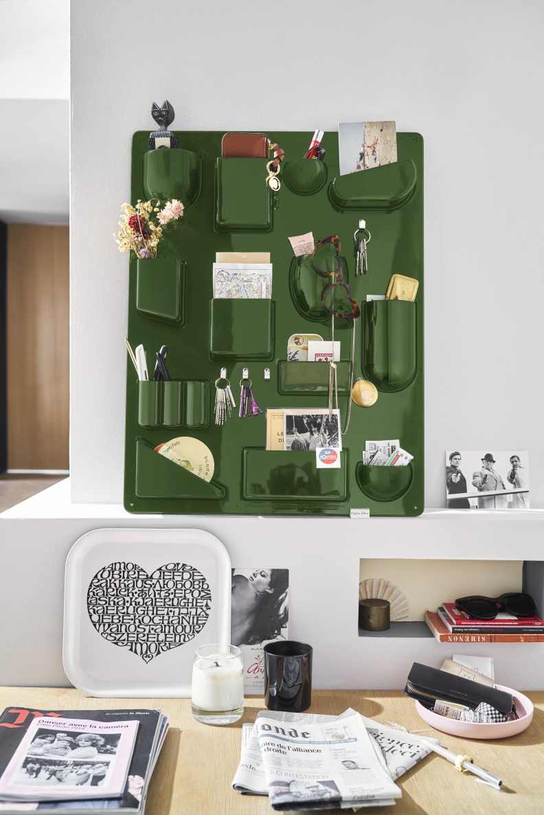 Detailaufnahme des grünen Vitra Uten.Silo Ordnungssystems an der Wand, gefüllt mit Büroartikeln und persönlichen Gegenständen.