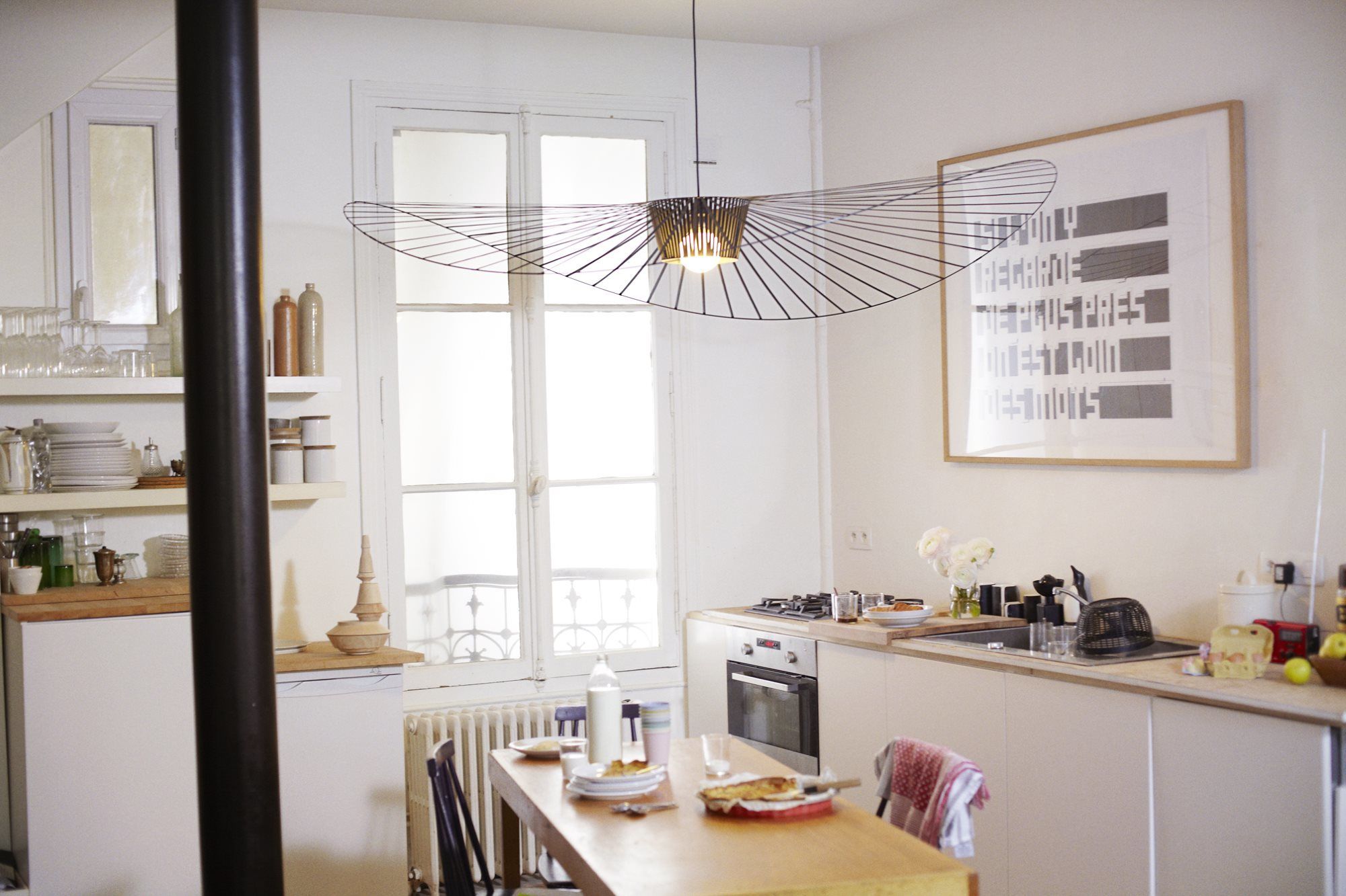 Weiße Vertigo Pendelleuchte von Petite Friture über Esstisch in heller Küche mit Fenster.