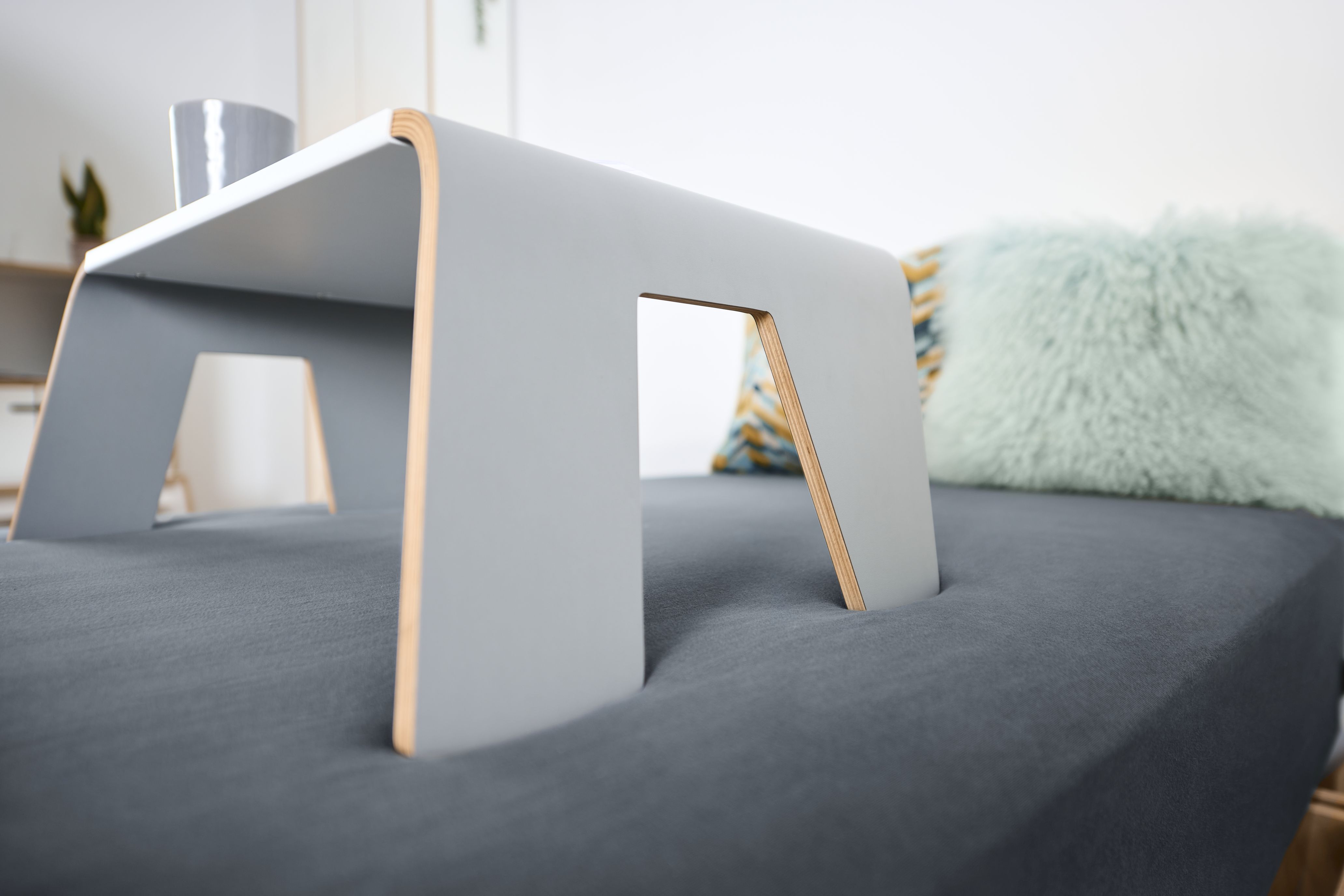 Graues Tojo Notebook-Tablett auf einem Bett, ideal als Frühstückstablett oder Laptop-Tisch.