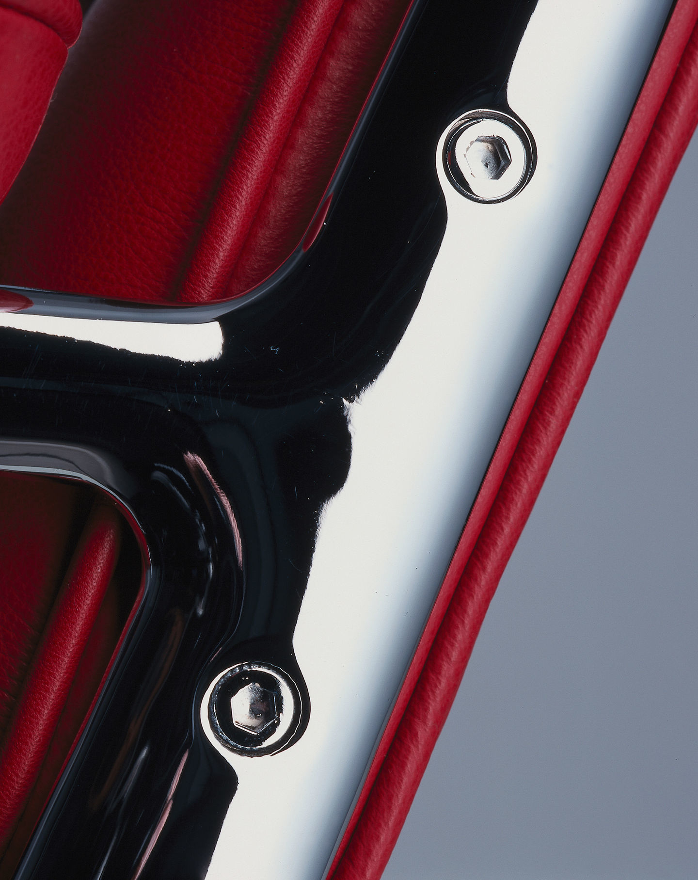 Detailaufnahme: Rotes Leder, Chrom und Schrauben am Vitra Lobby Chair ES 108.