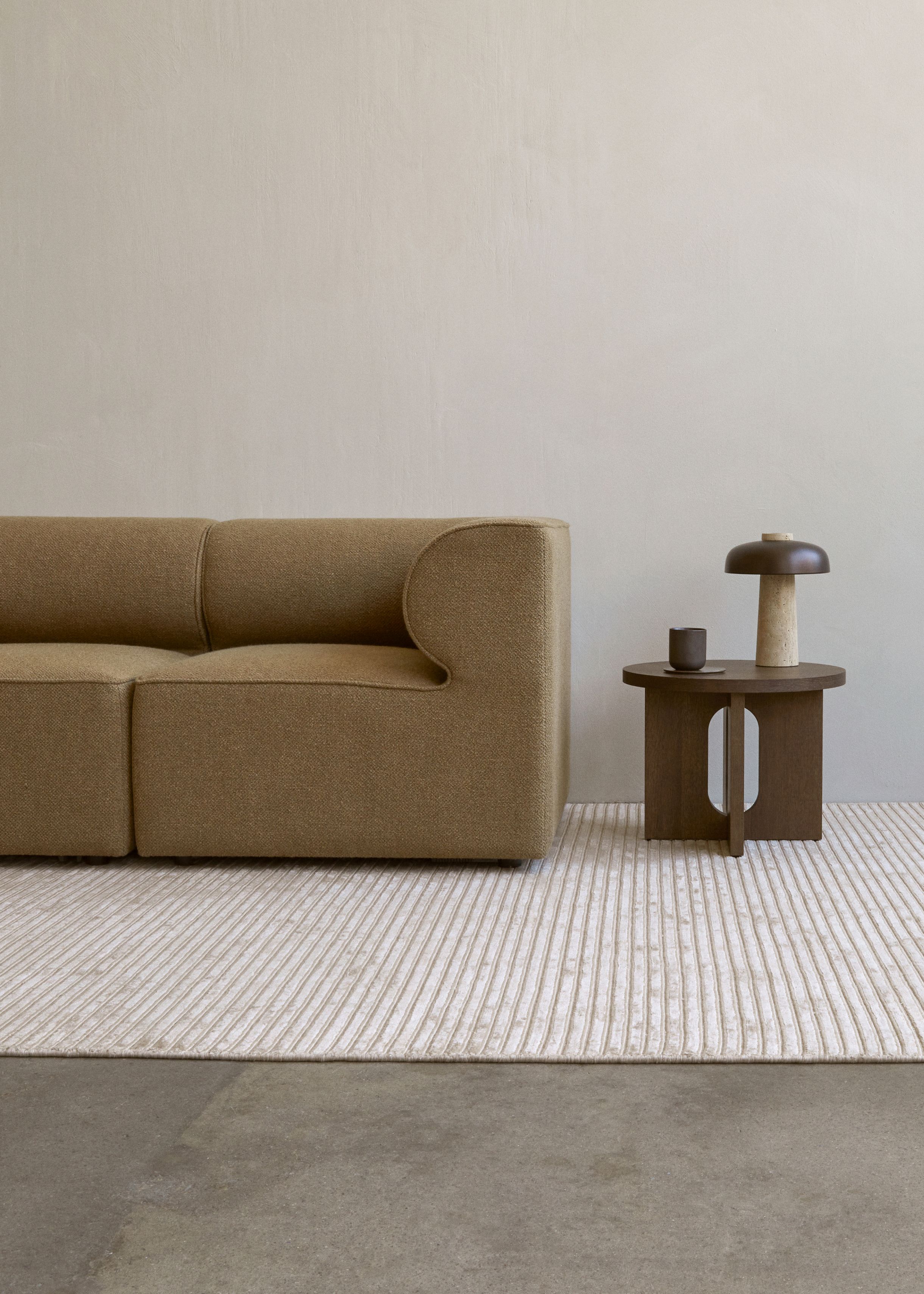 Androgyne Beistelltisch von Audo mit dunklem Eichengestell neben einem beigen Sofa auf einem Teppich.