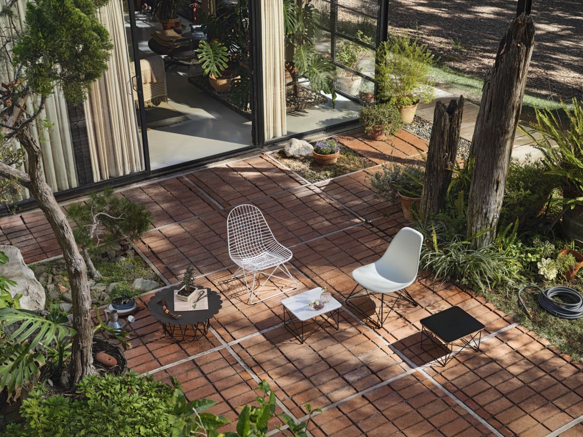 Draufsicht: Eames Fiberglass Chair LSR Stuhl von Vitra im Garten mit Tischen.