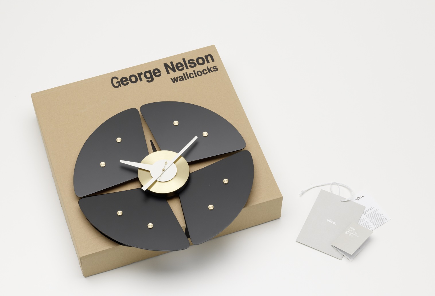 Vitra Petal Clock Wanduhr in Schwarz und Gold auf Karton, modernes Design für Wohnzimmer.