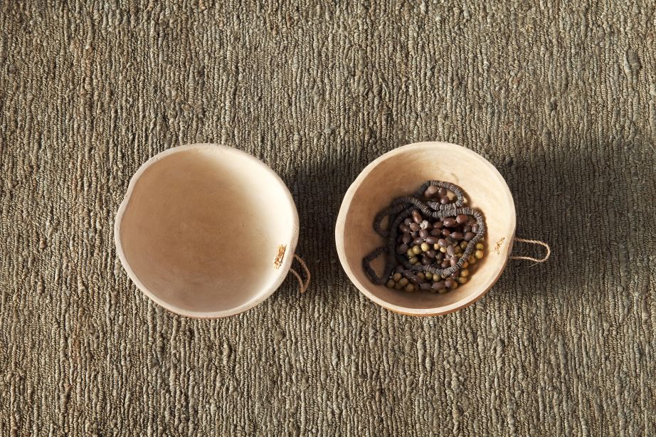 Detailaufnahme Nanimarquina Earth Rug Teppich Khaki 250x350cm mit zwei Schalen, eine mit einer Kette.