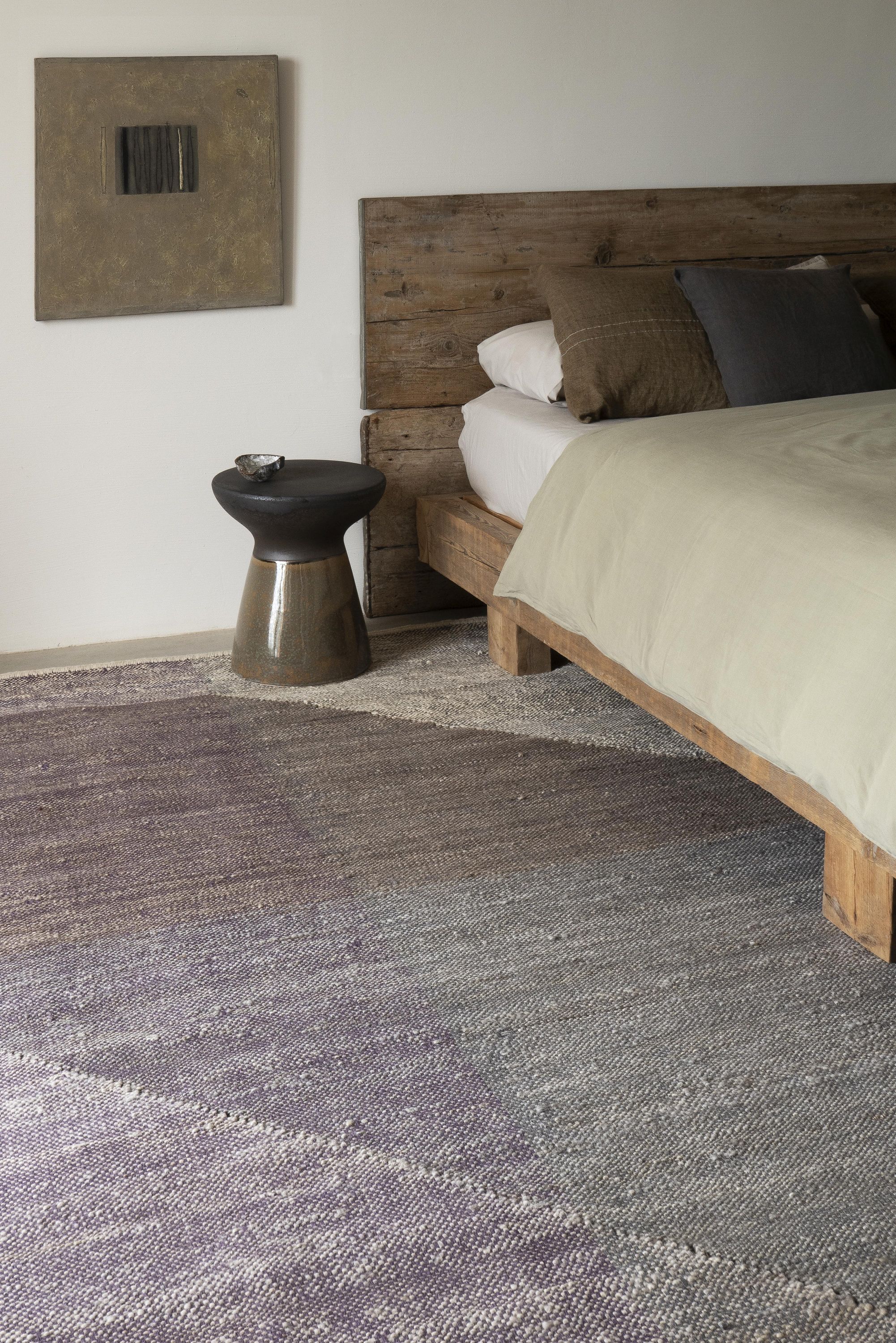 Nanimarquina Capas Teppich, 170x240 cm, im Schlafzimmer mit Holzbett und Nachttisch. Moderner Teppich in Grau und Lila.
