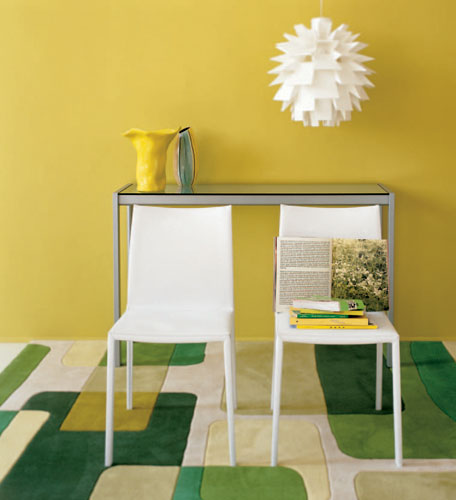 Weißer Stuhl Lea ohne Armlehne von Zanotta vor gelber Wand und grünem Teppich. Design Stuhl.