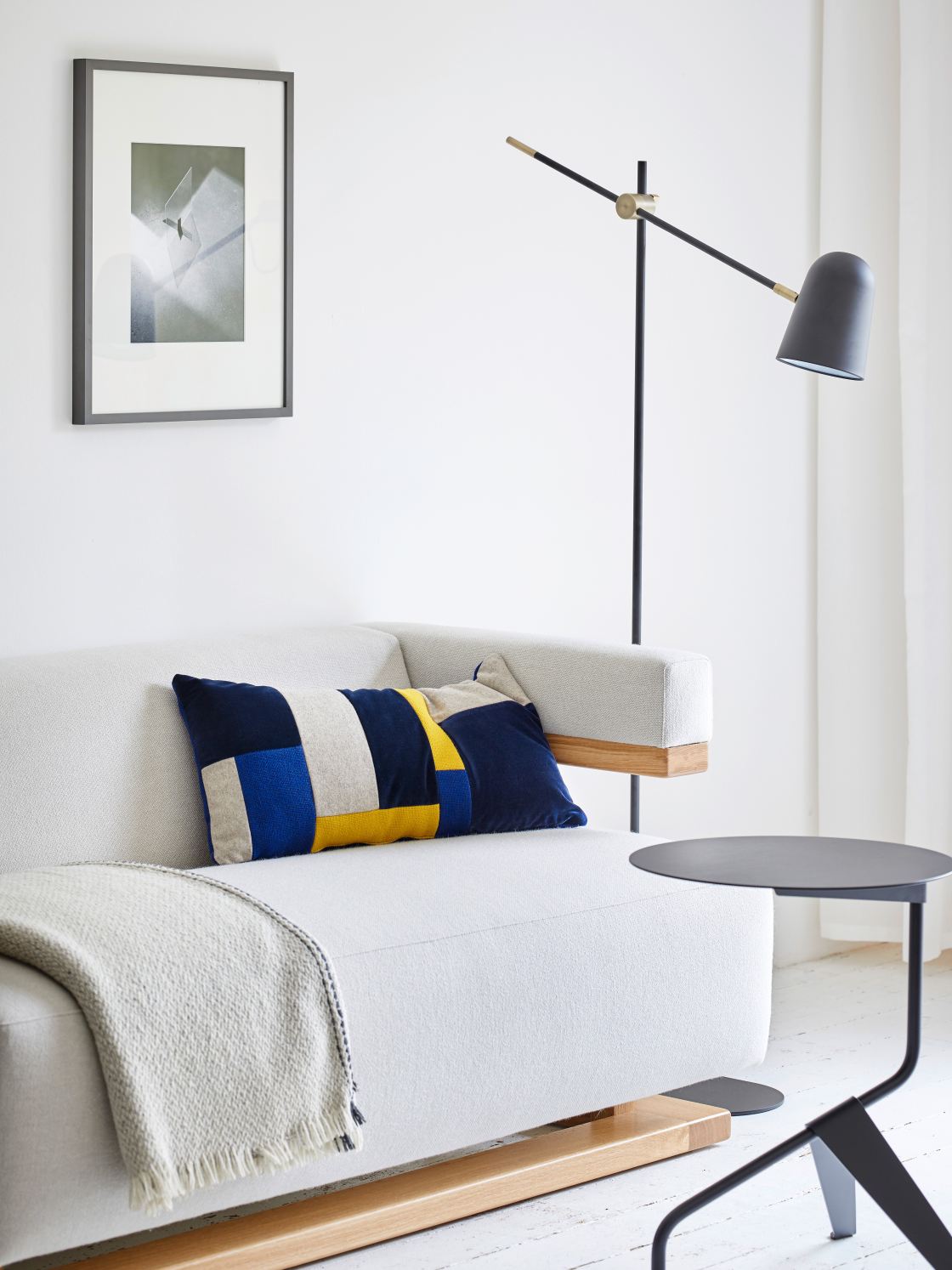 Weißer Tecta K5 Beistelltisch neben Sofa mit Kissen und Lampe. Moderner Couchtisch für Wohnzimmer.