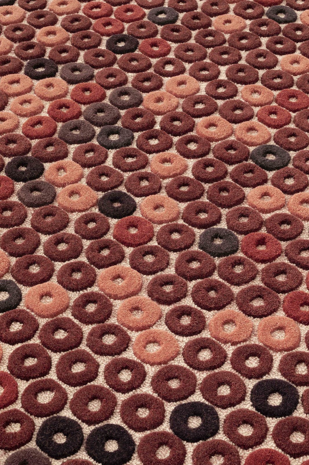 Detailaufnahme des Chimos Rug Teppichs mit braunen und beigen Donut-förmigen Elementen für Wohnzimmer und Schlafzimmer.