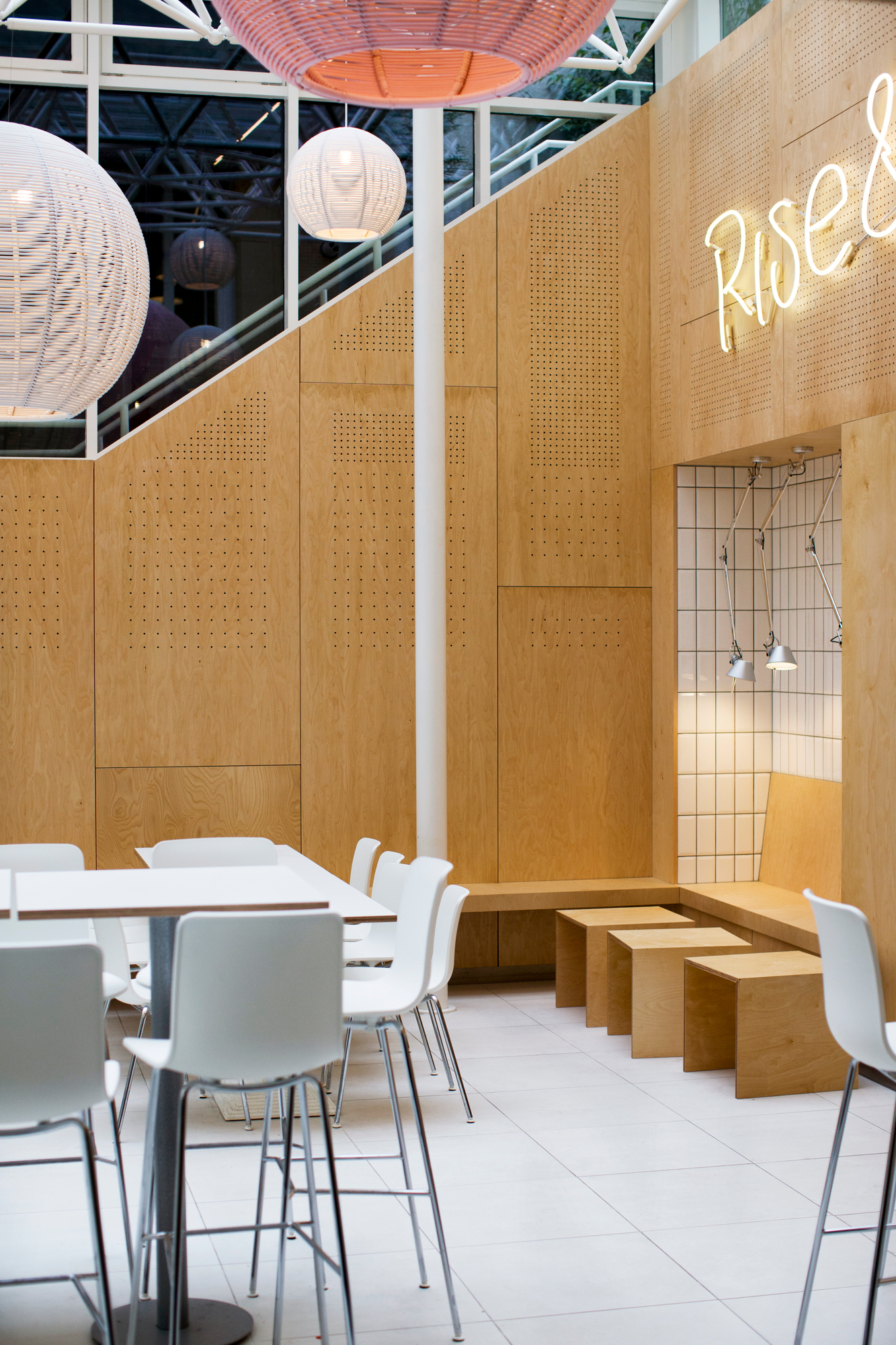 Helle Gastronomie mit weißen Hal Barhockern von Vitra an weißen Tischen.