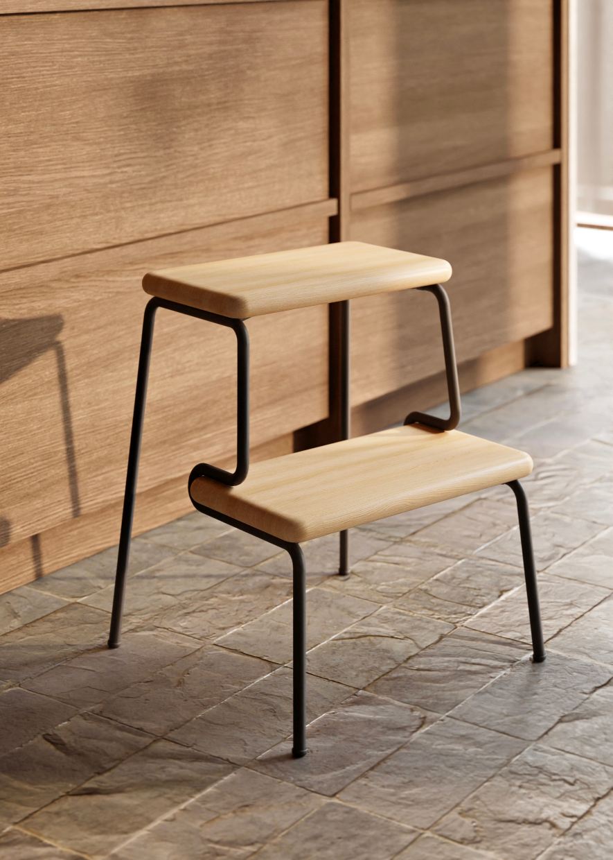 Slalom Step Stool Tritthocker: Moderner, zweistufiger Hocker aus hellem Holz und schwarzem Metall.