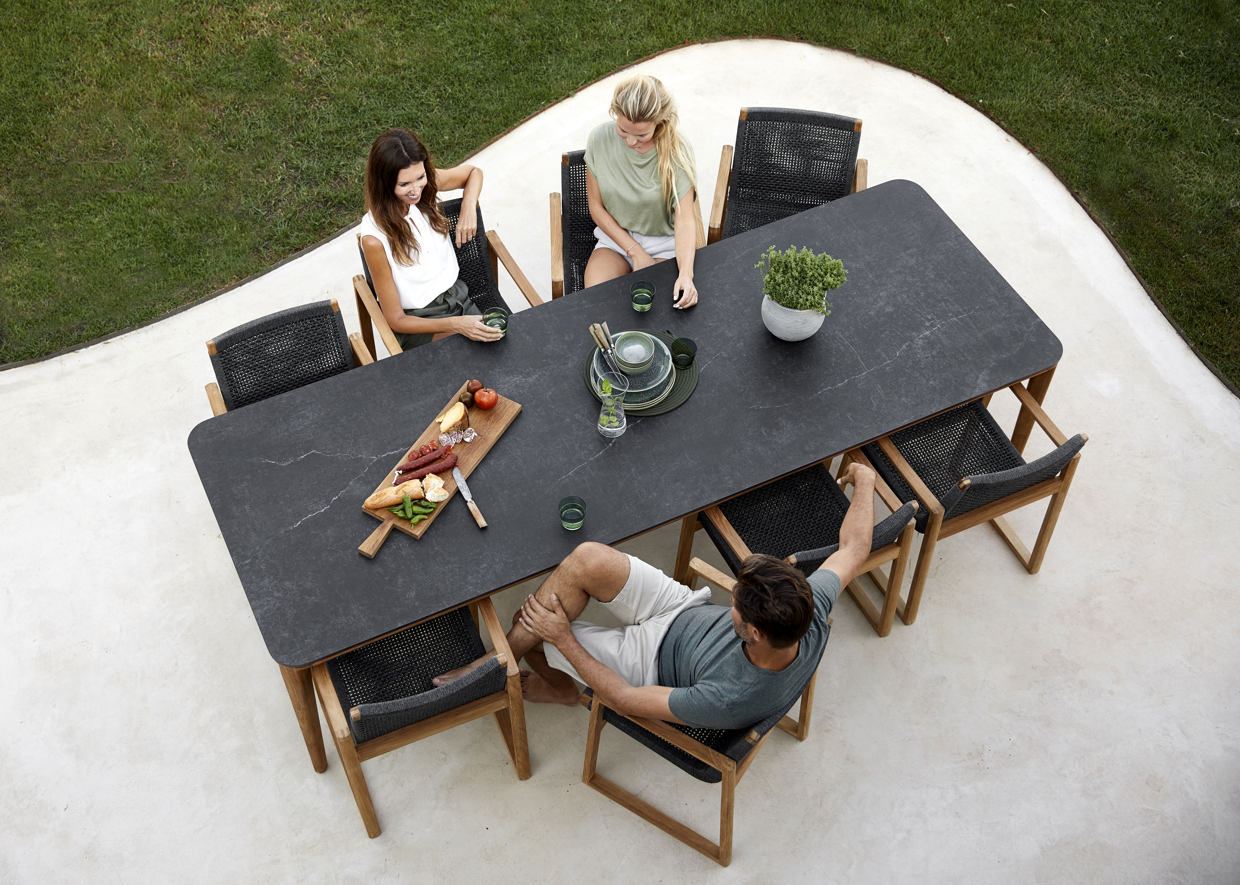 Draufsicht: Menschen sitzen an einem Tisch auf Cane-Line Endless Sesseln im Garten.