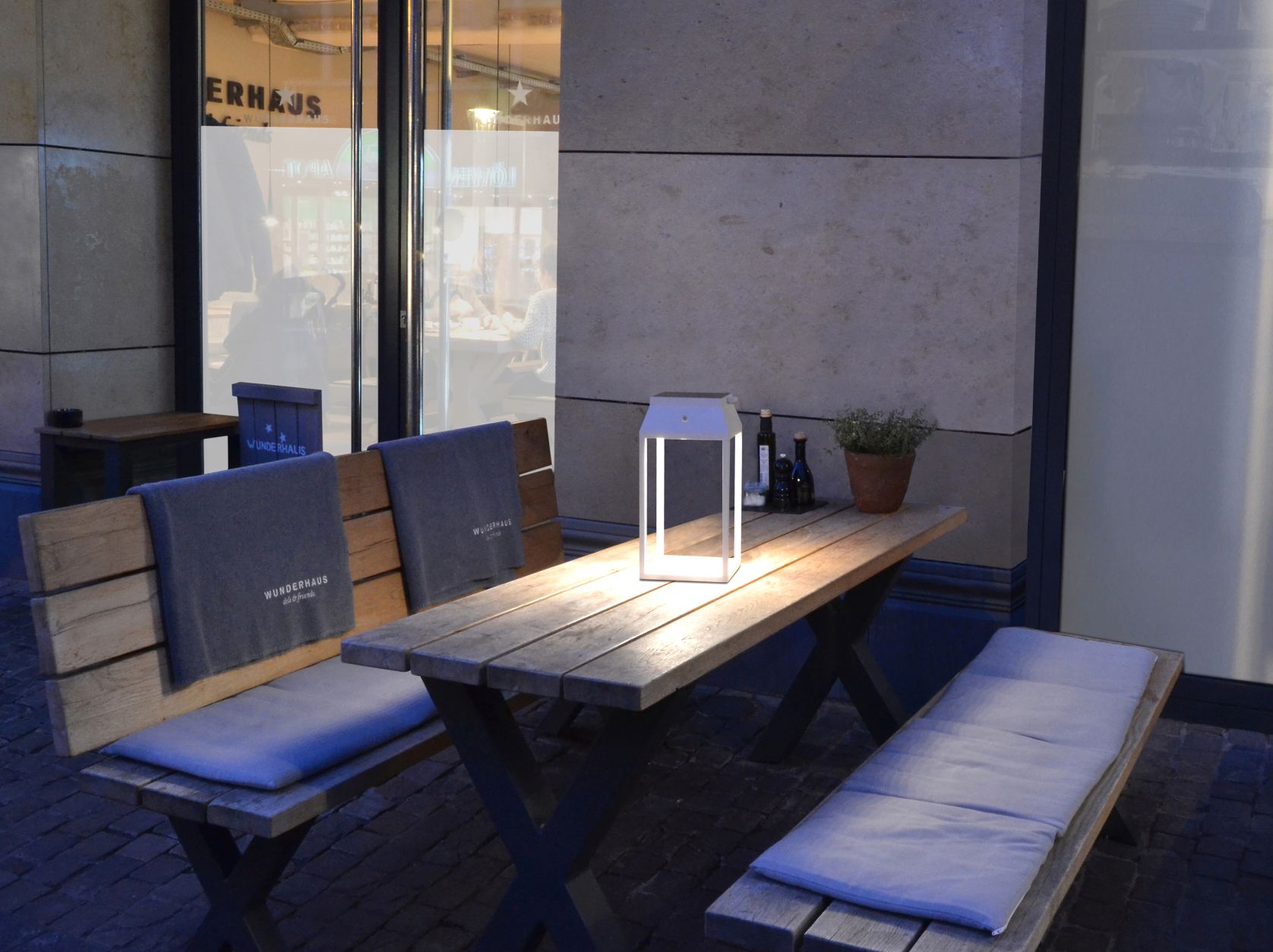 Louis 36 Solar Laterne Moree auf Holztisch mit Bänken, stimmungsvolle Außenbeleuchtung.