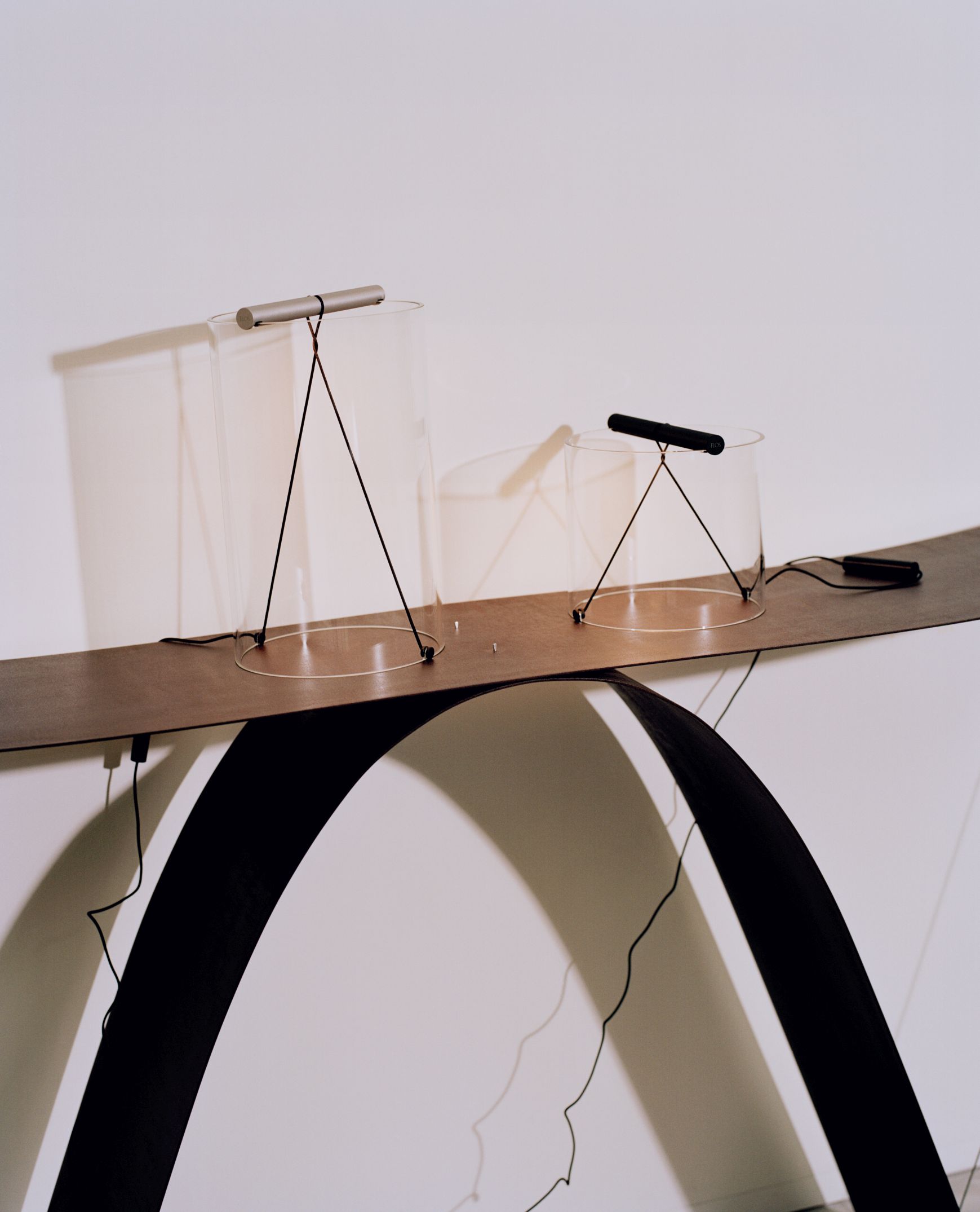 To-Tie T2 LED Tischleuchte von Flos, schwarz eloxiert, modernes Design mit transparentem Zylinder und filigranen Aufhängungen.