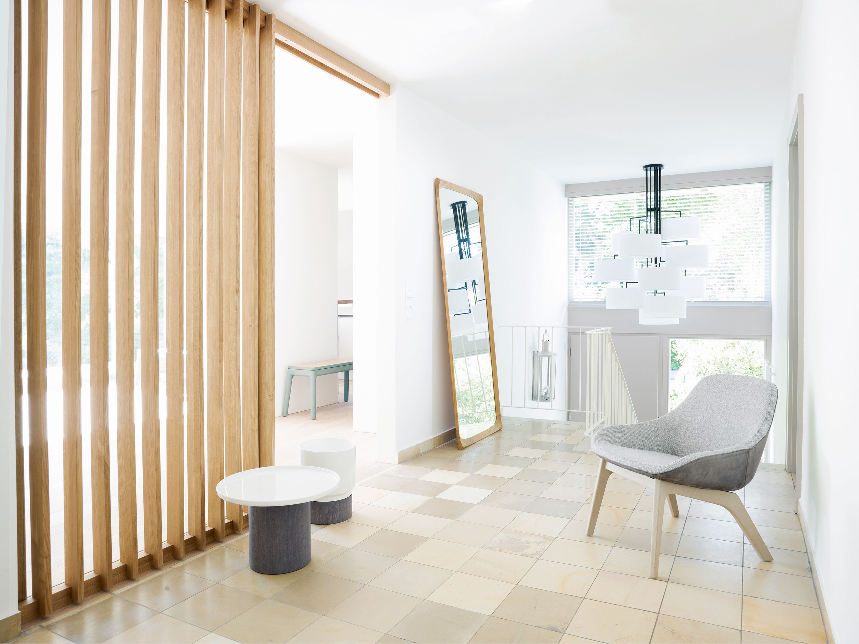 Heller Raum mit NOON 12 Deckenleuchte in Warmgrau, Stuhl und minimalistischer Einrichtung.