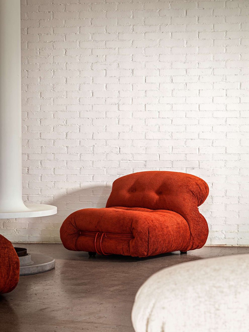 Roter Soriana Sessel von Cassina: Moderner Design-Sessel mit Stoffbezug vor einer weißen Ziegelwand.