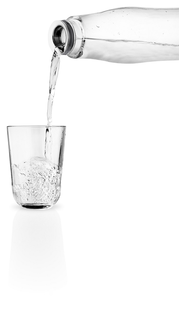 Wasser wird aus einer Eva Solo Glaskaraffe in ein Glas gegossen. Karaffe mit Deckel.