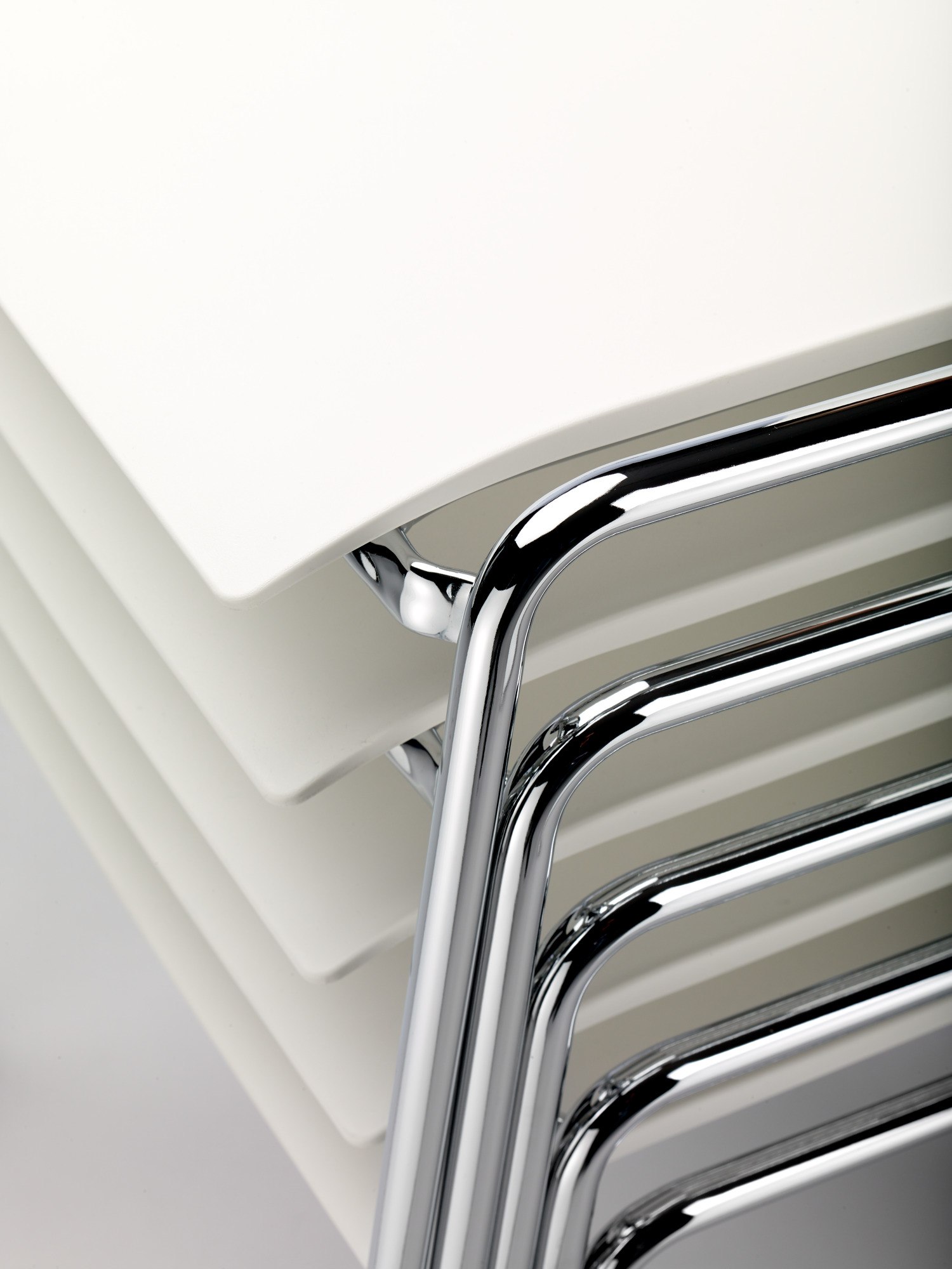 Detailaufnahme von gestapelten, weißen S 260 Stühlen ohne Armlehne von Thonet mit verchromtem Stahlrohrgestell.
