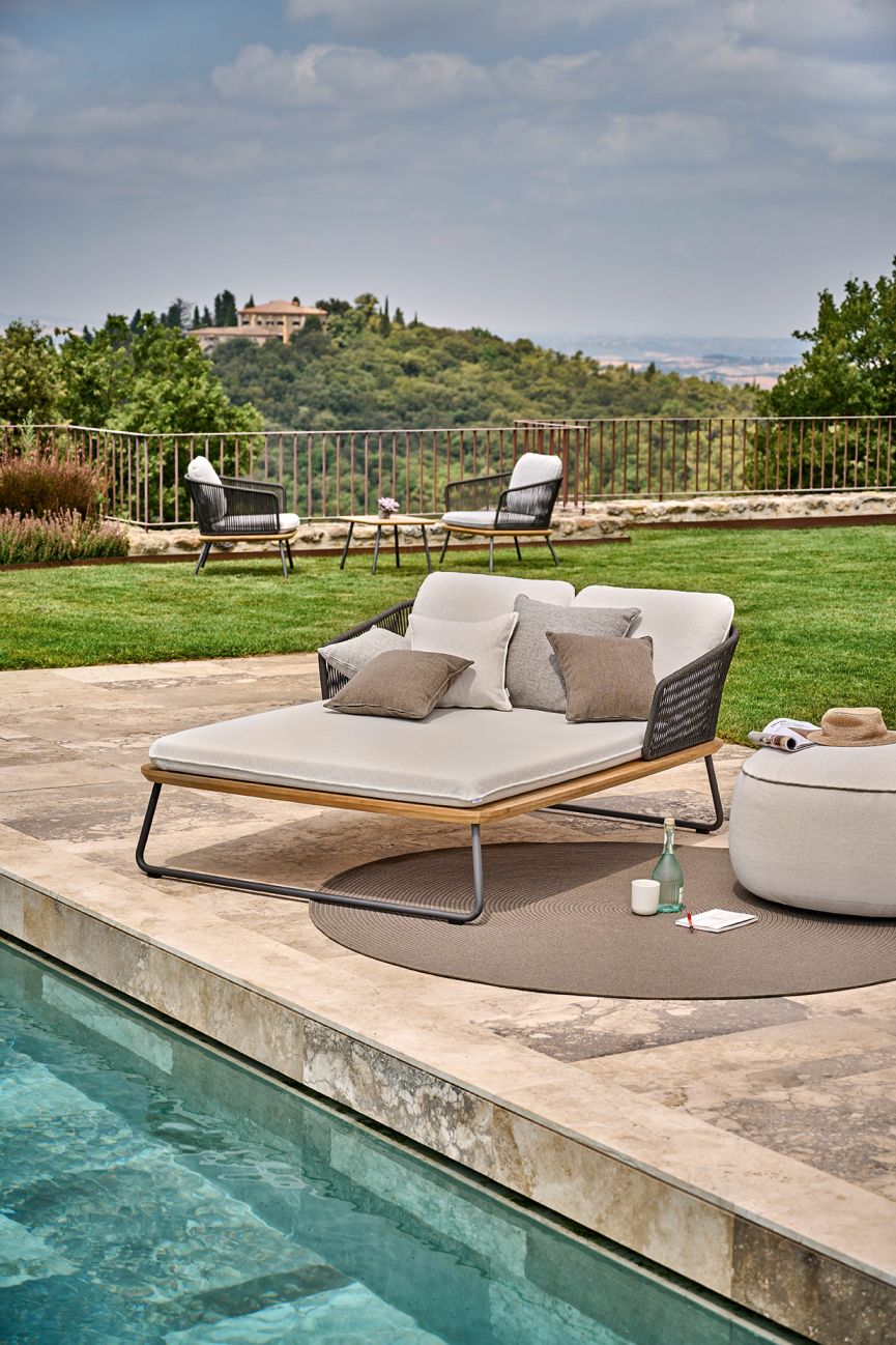 Maliha Lounge Hocker von Weishäupl, runder Outdoor-Sitzhocker in Beige neben einer Poollandschaft.