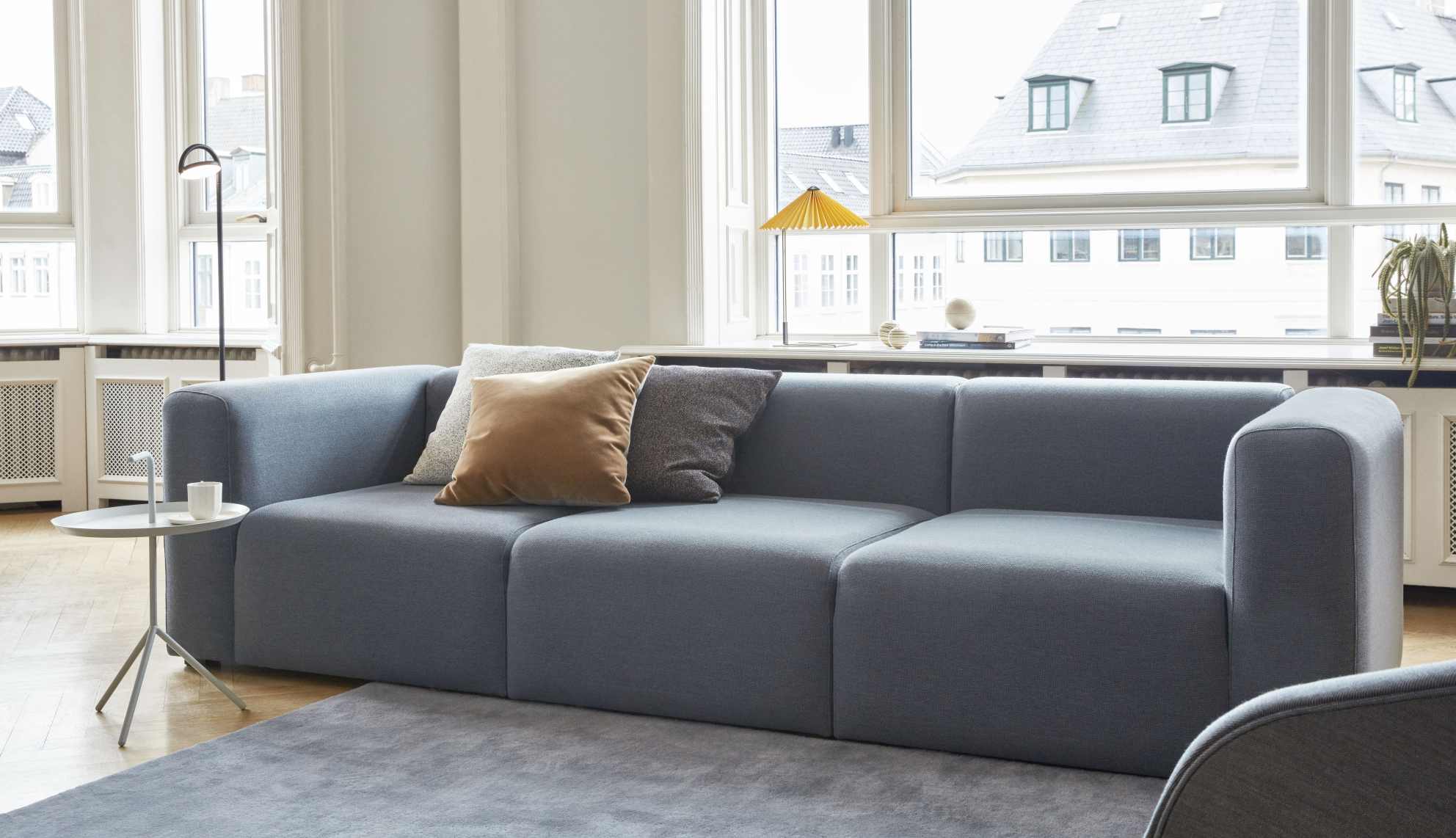 Mags Sofa 3-Sitzer im modernen Wohnzimmer mit grauen Teppich und Kissen. Stoffbezug Bolgheri.