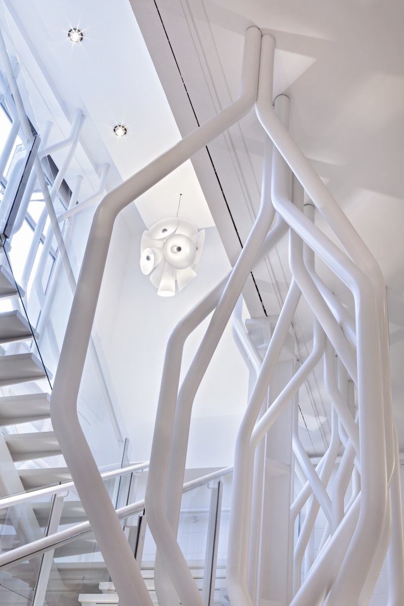 Weiße Nebula Pendelleuchte von Flos, gesehen durch ein weißes Treppengeländer, modernes Design.