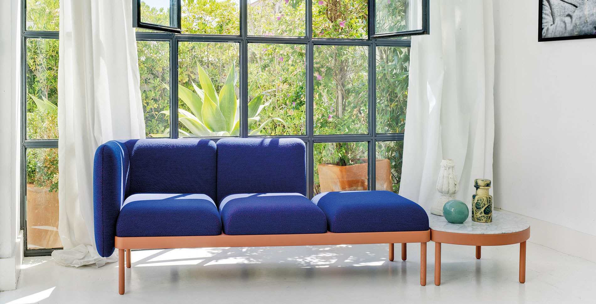 Mosaico Sitzbank von Sancal, blaues modulares Sofa mit Beistelltisch vor Fenster.