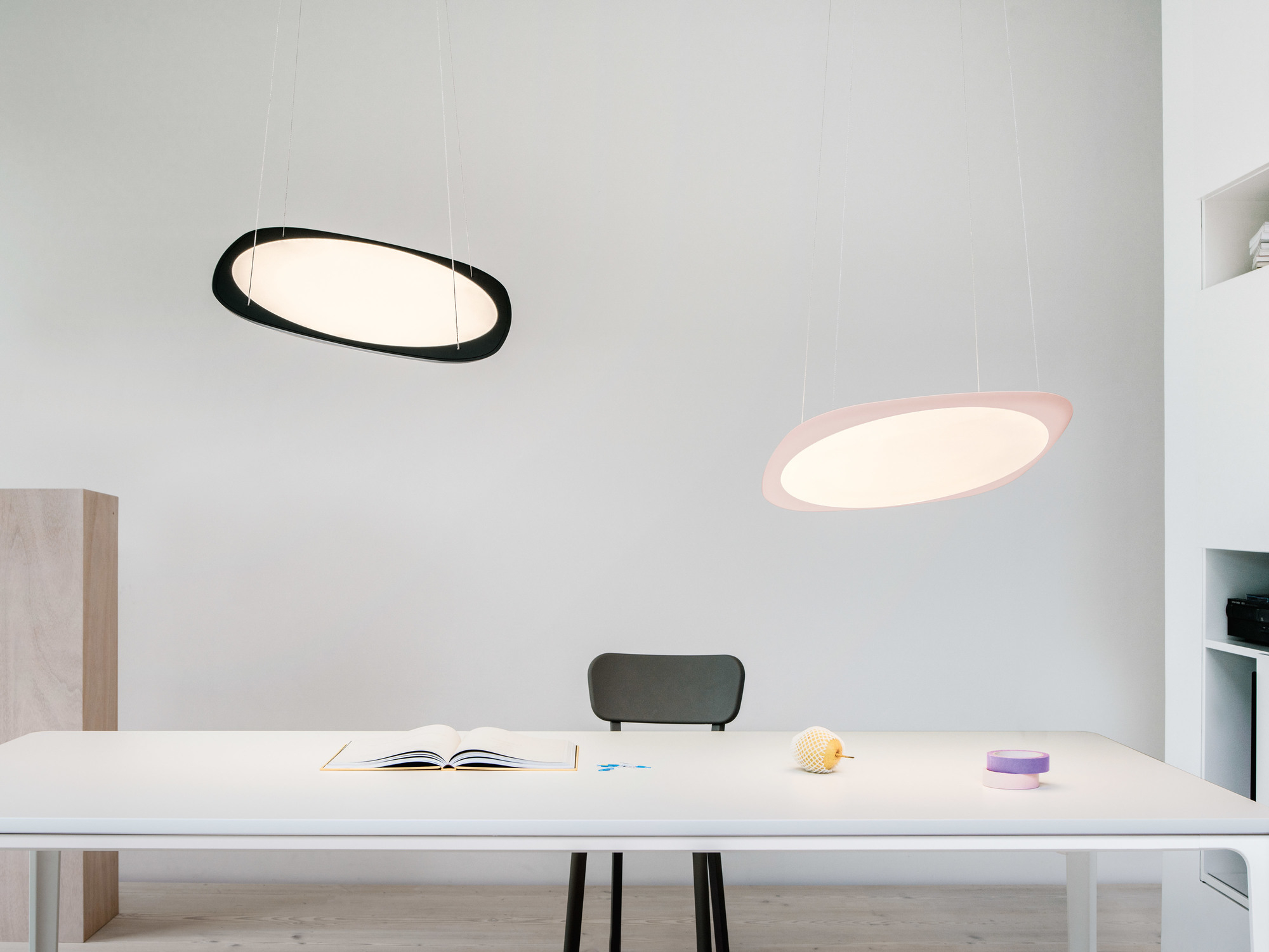 Zwei Flying Pendelleuchten von Tobias Grau in Schwarz und Rosa über einem Schreibtisch.