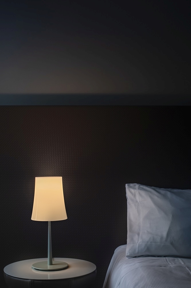 Weiße Birdie Easy Tavolo Tischleuchte von Foscarini auf Nachttisch neben Bett.