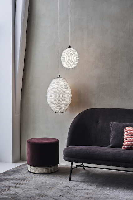 Zwei CALEO Pendelleuchten von Le Klint hängen über einem Sofa in einem Wohnzimmer.