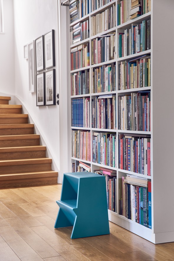 Blauer Tritthocker von Richard Lampert vor Bücherregal und Treppe. Design Tritthocker für Kinder.