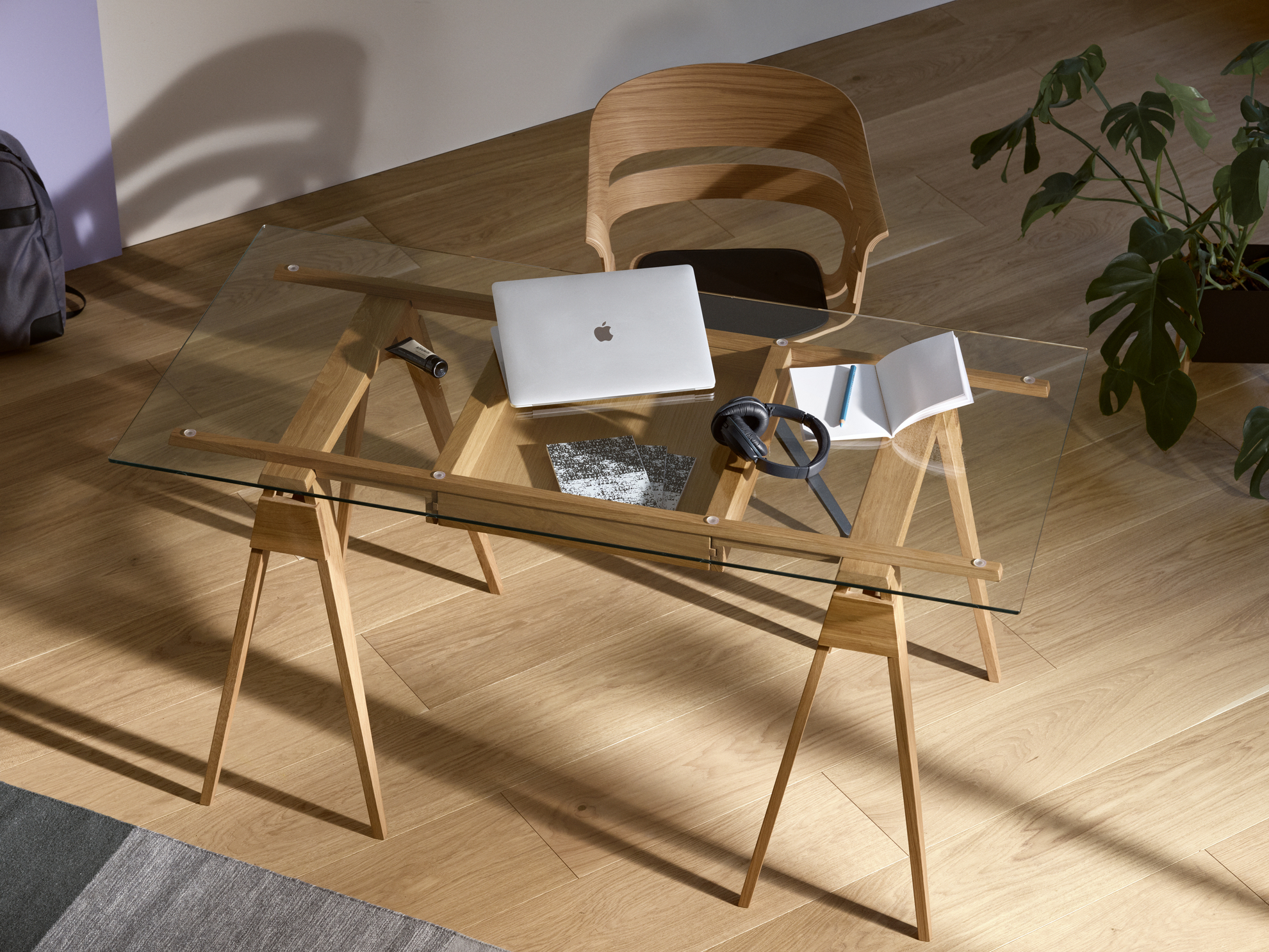 Arco Desk von Design House Stockholm: Glas-Schreibtisch mit Holzgestell, Laptop, Kopfhörer und Notizbuch.