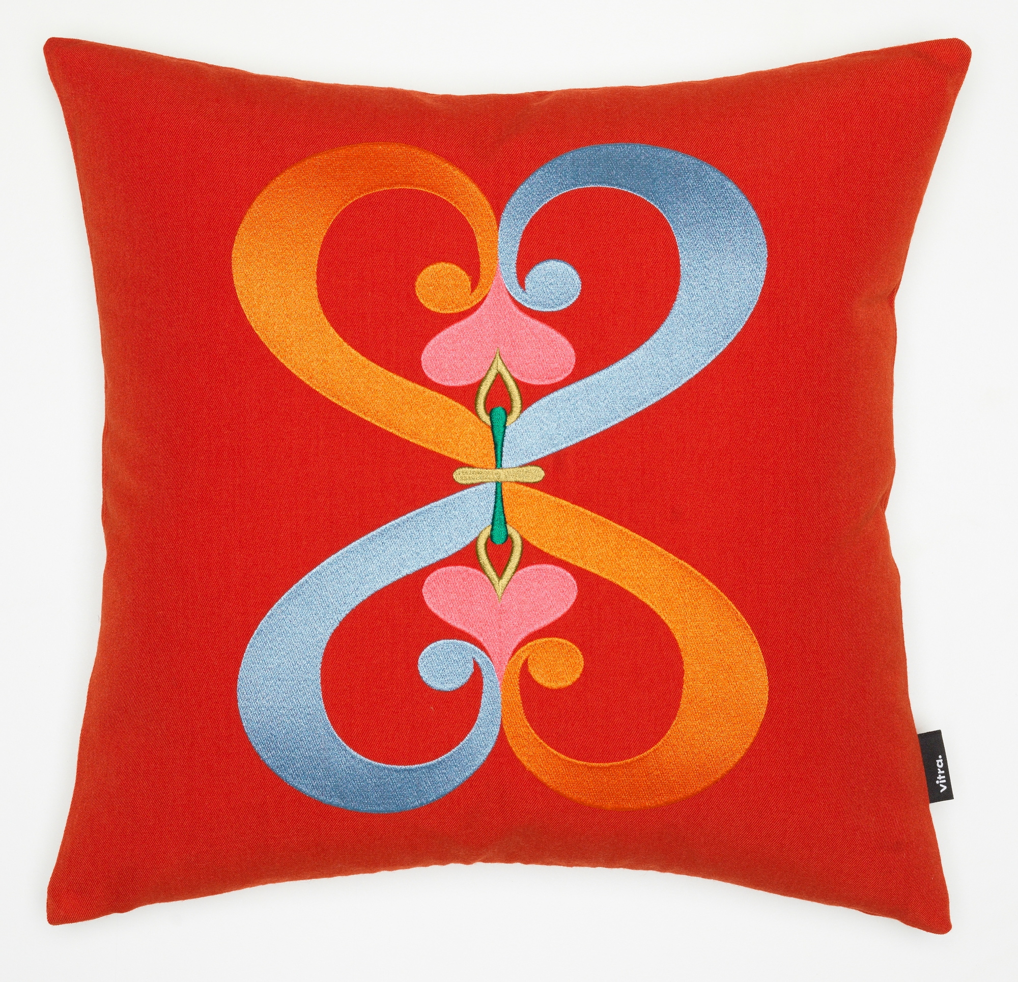 Vitra Kissen mit rotem Bezug und gesticktem, abstraktem Doppelherz-Motiv in Orange und Blau.