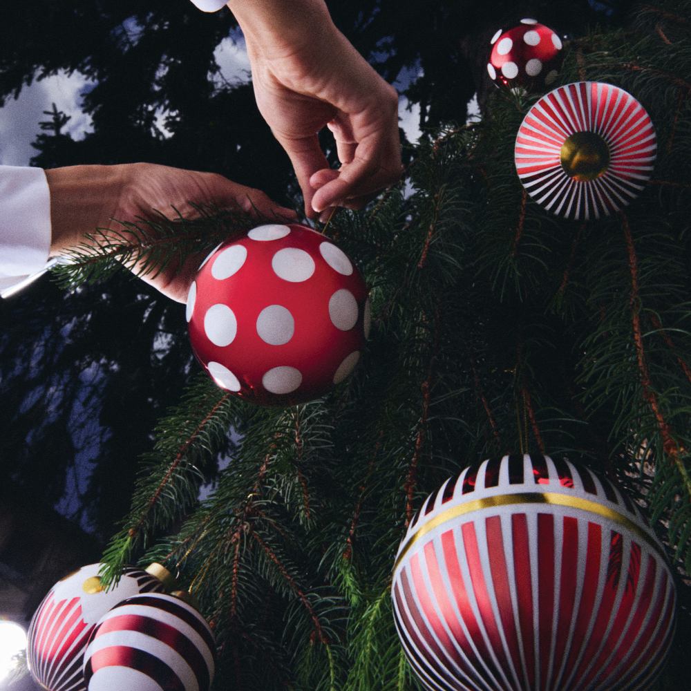 Hand dekoriert Tannenbaum mit Alessi Weihnachtskugel. Rote Christbaumkugeln mit Mustern. Festliche Weihnachtsdekoration.