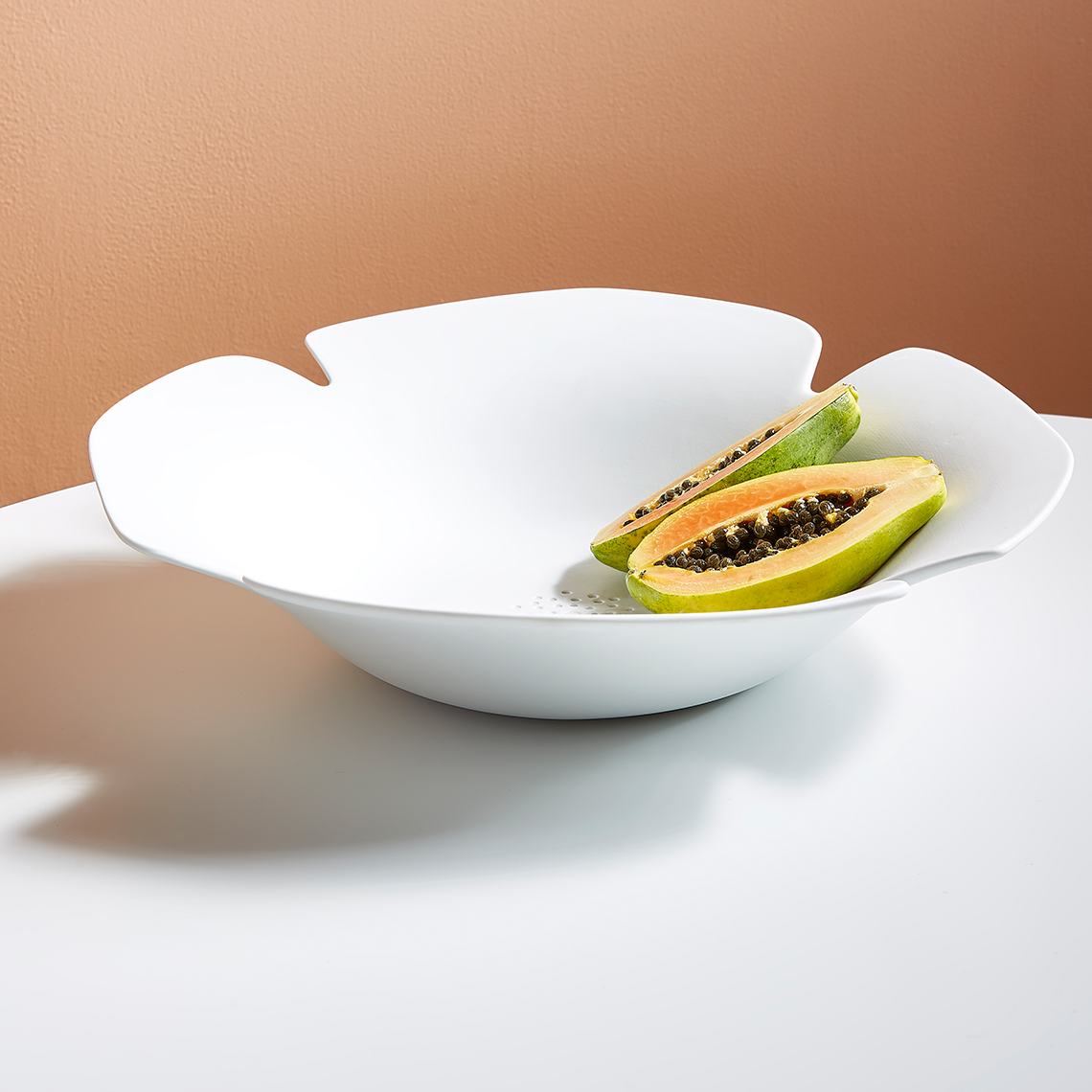 Weiße "Das Blühende Leben" Schale von Räder mit angeschnittener Papaya. Dekorative Obstschale für Küche und Tisch.