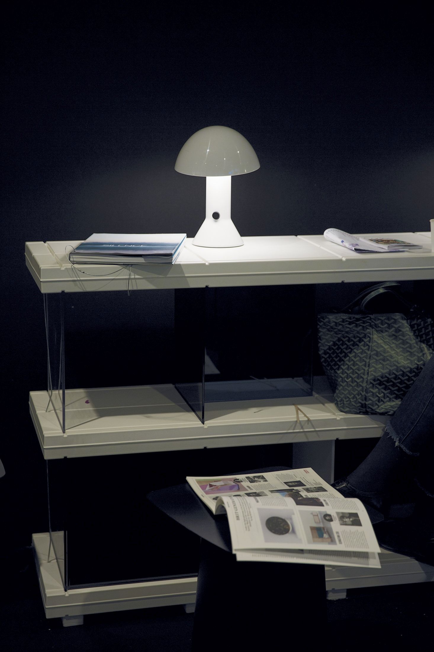 Elmetto Tischleuchte von Martinelli Luce auf einem weißen Regal mit Zeitschriften.