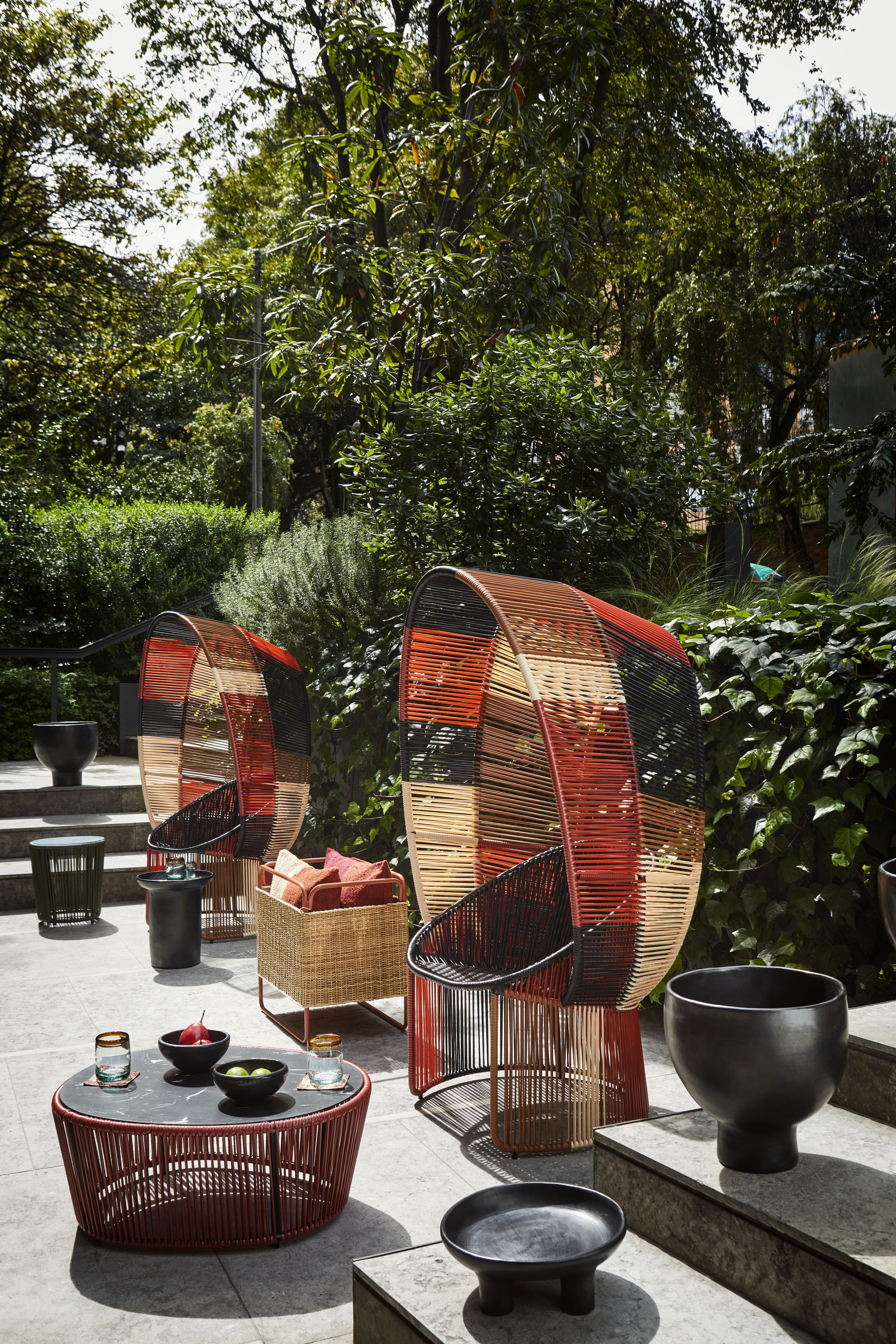 Cartagena Reina Outdoor Sessel: Zwei farbenfrohe Korbsessel mit passendem Tisch und Deko im Garten.